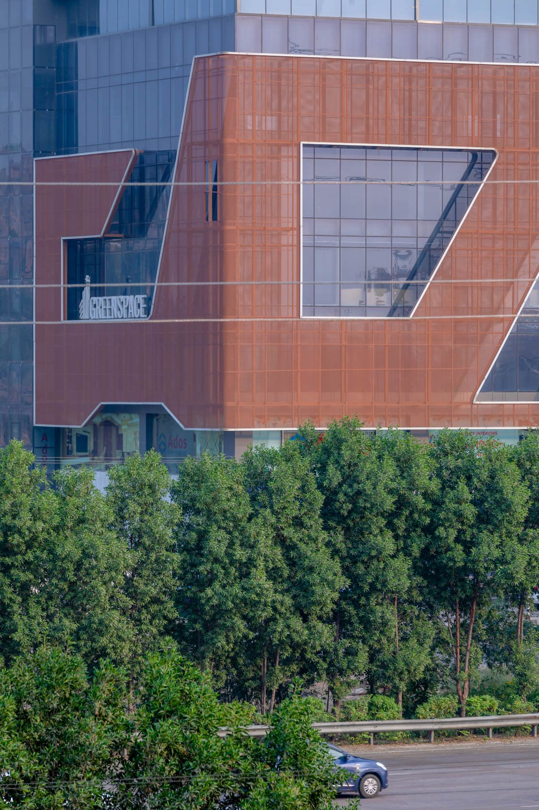 ommercial architecture photography capturing a close-up facade detail of a modern office building with terracotta cladding and integrated landscaping