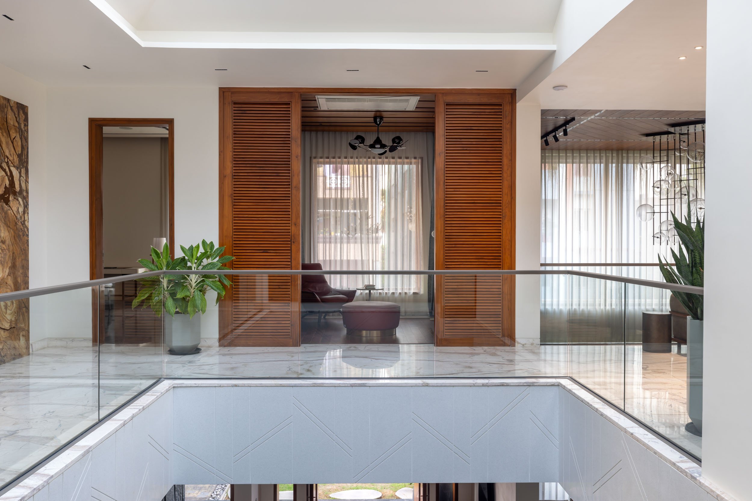 Professional interior architectural photography of a modern residential home, highlighting a bright, multi-level living space with expansive glass windows and a seamless indoor-outdoor connection