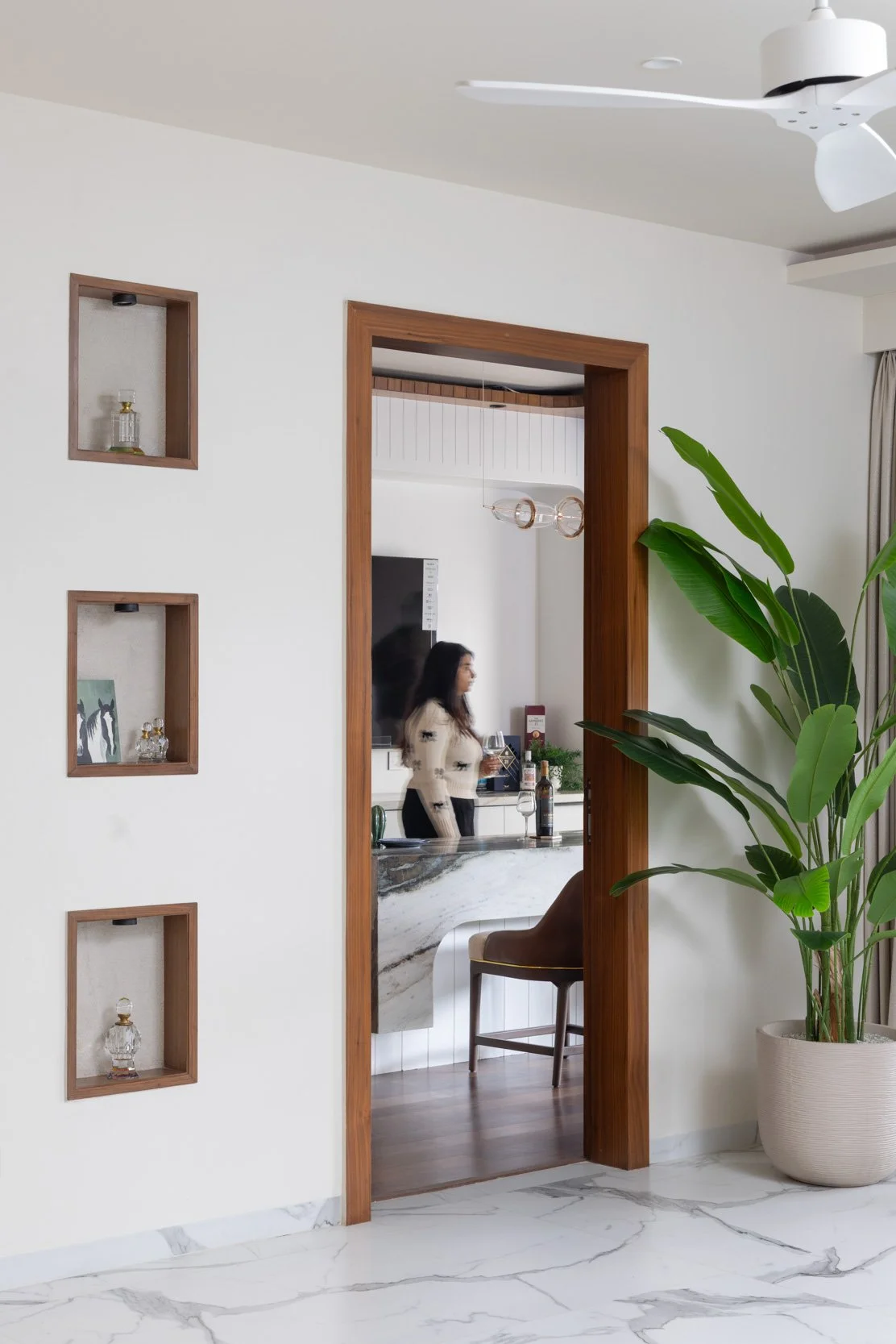 Professional interior photography of a residential hallway highlighting a wooden doorway, framed wall art, and an indoor plant.