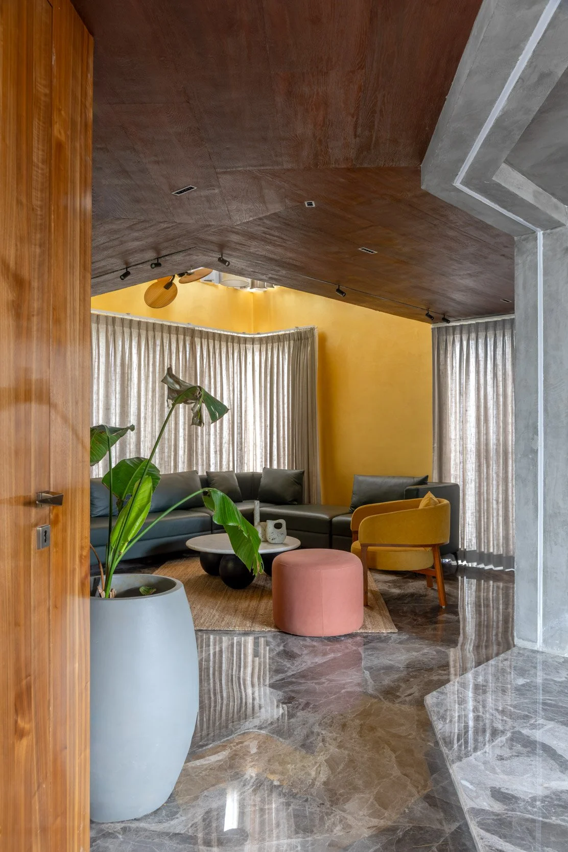 Professional interior architectural photography of a vibrant residential space, beautifully framed through a wooden doorway and highlighting a bold yellow accent wall