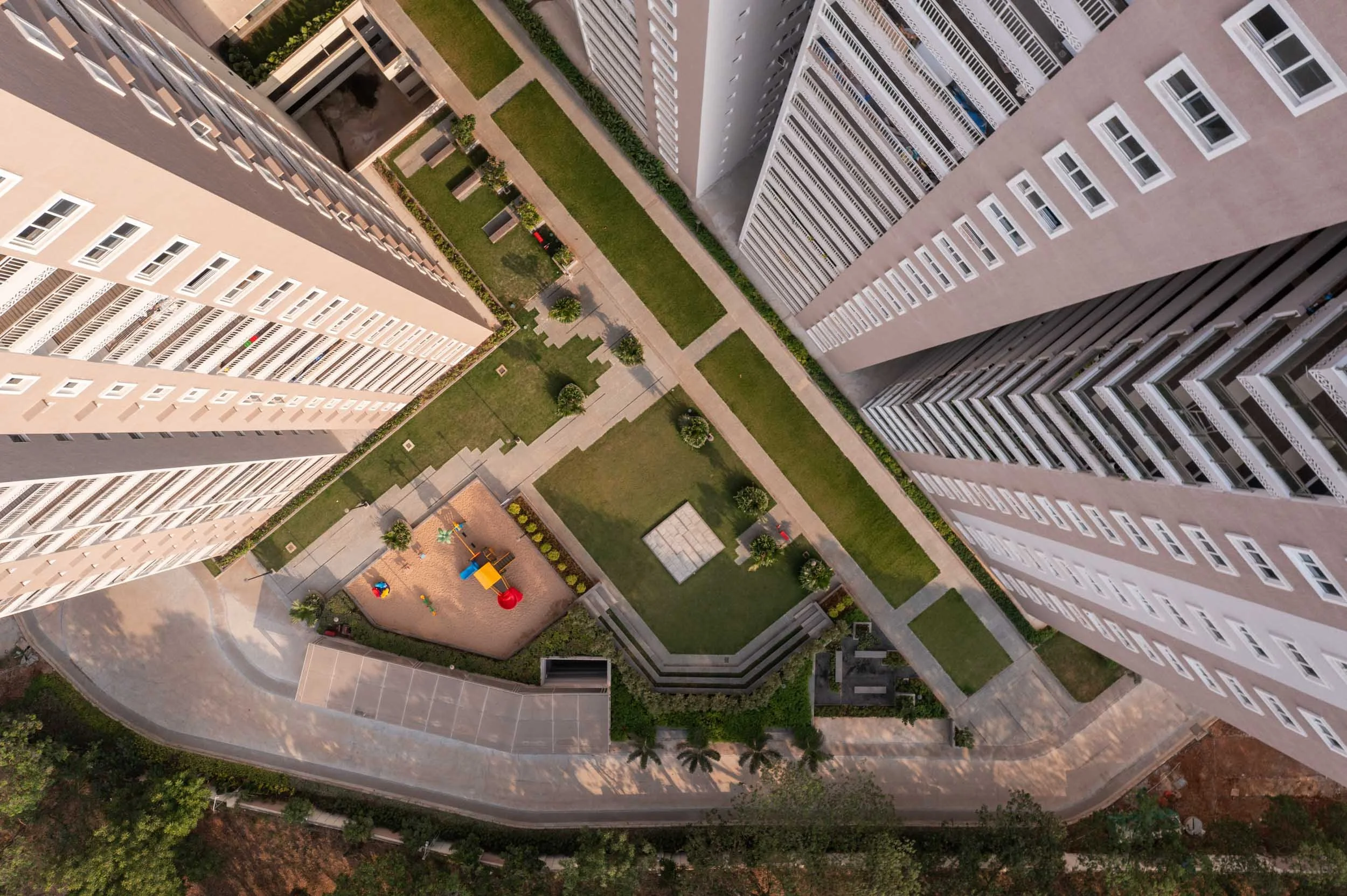 Aerial real estate photography featuring a top-down drone shot of modern residential high-rises, highlighting urban density and integrated green spaces