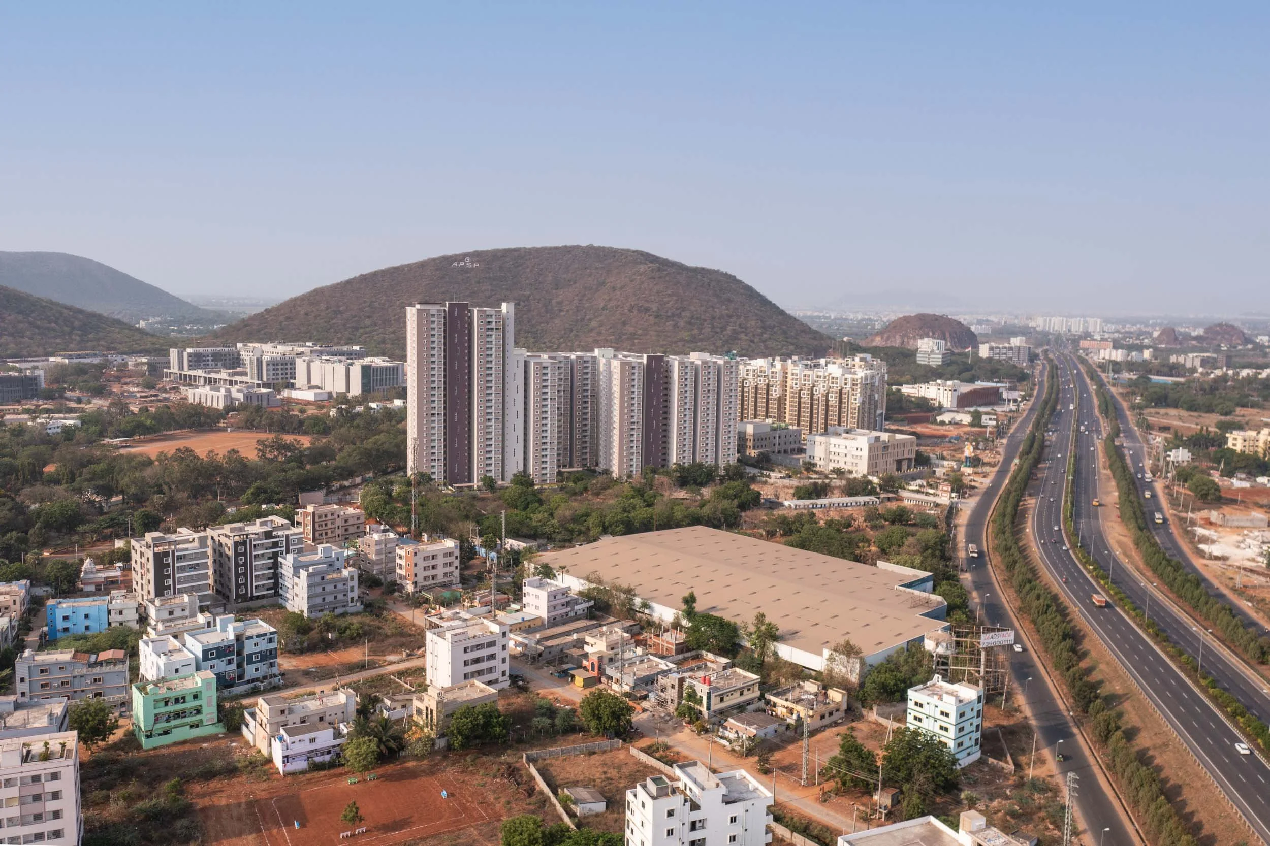 Aerial real estate photography showcasing city infrastructure, residential developments, and scenic mountain views from a bird's-eye perspective