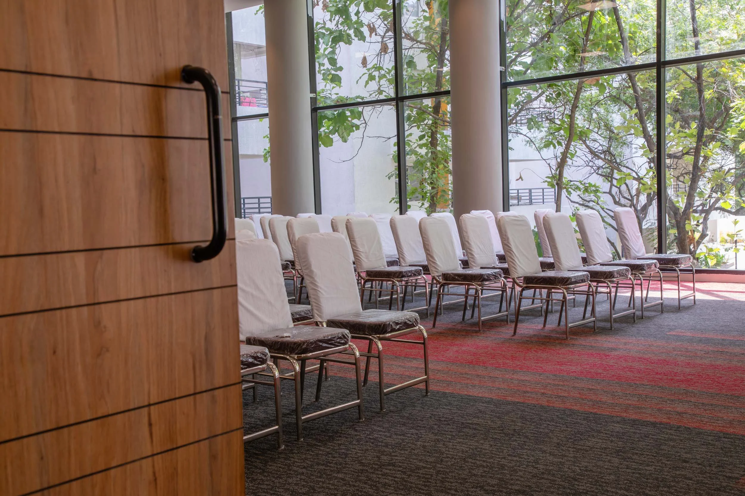 Commercial interior photography showcasing a spacious presentation hall or conference room with natural lighting, contemporary seating arrangements, and custom wood finishes