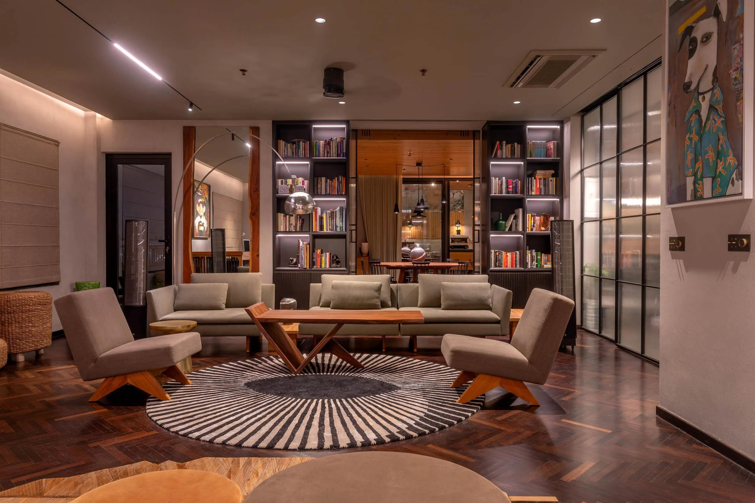 Modern residential foyer featuring a dark console table, colorful framed artwork, and warm wall-mounted accent lighting.