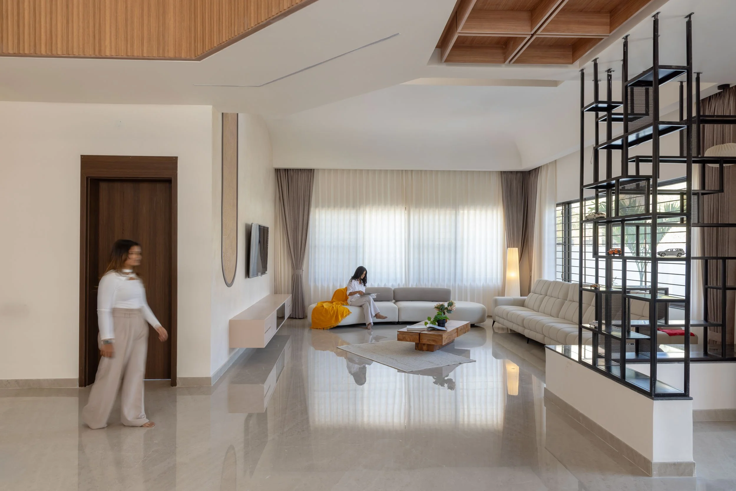 Professional interior photography of a spacious, modern residential living area featuring highly reflective polished floors and a custom wooden ceiling