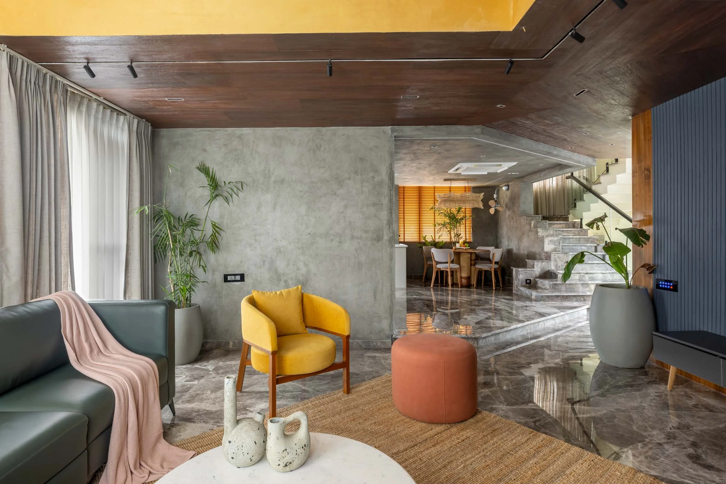 Professional interior architectural photography of a modern living room, highlighting a warm wooden ceiling, textured walls, and vibrant accent furniture.
