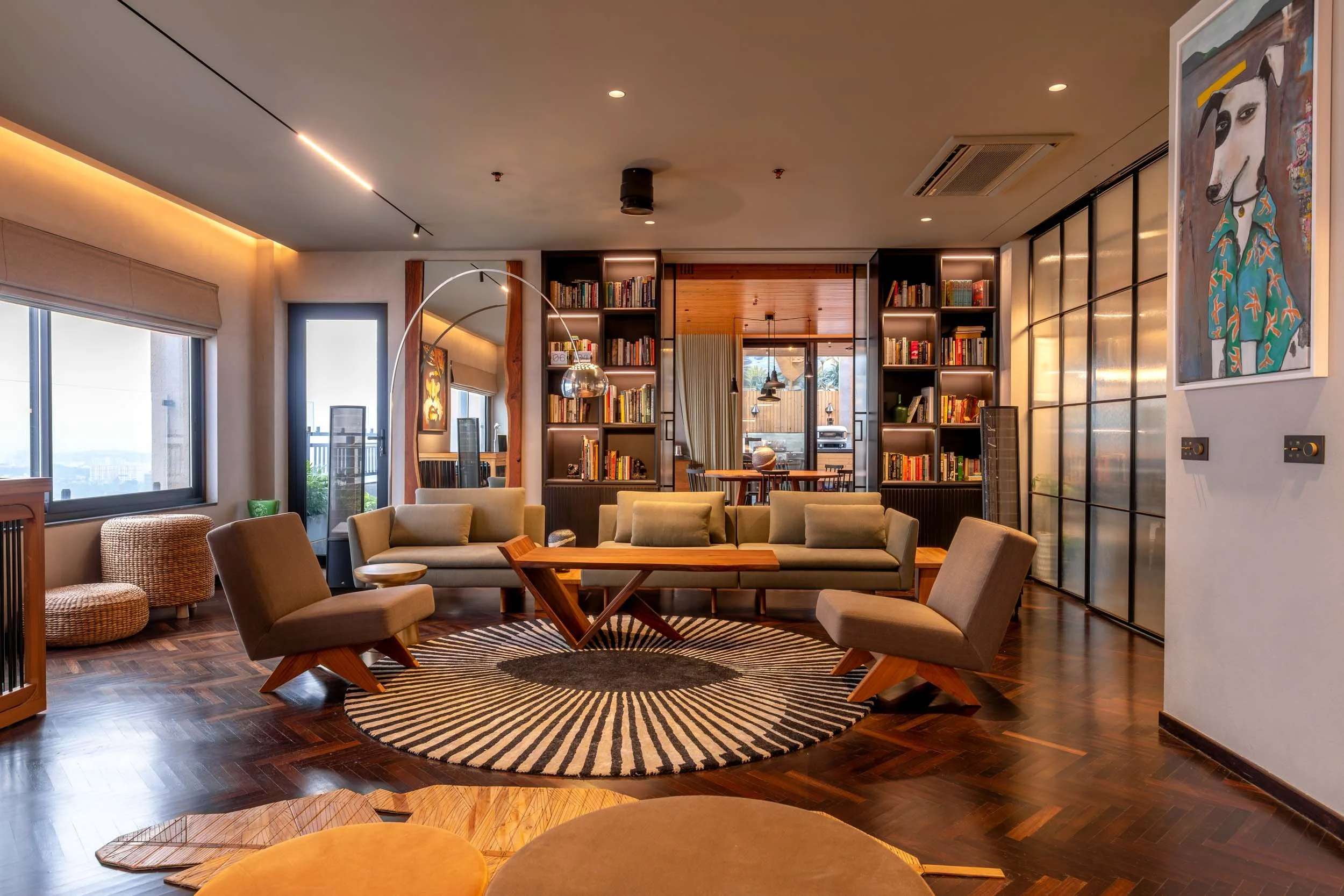 Architectural lighting design in a modern living room featuring a circular patterned rug, wooden floors, and contemporary furniture