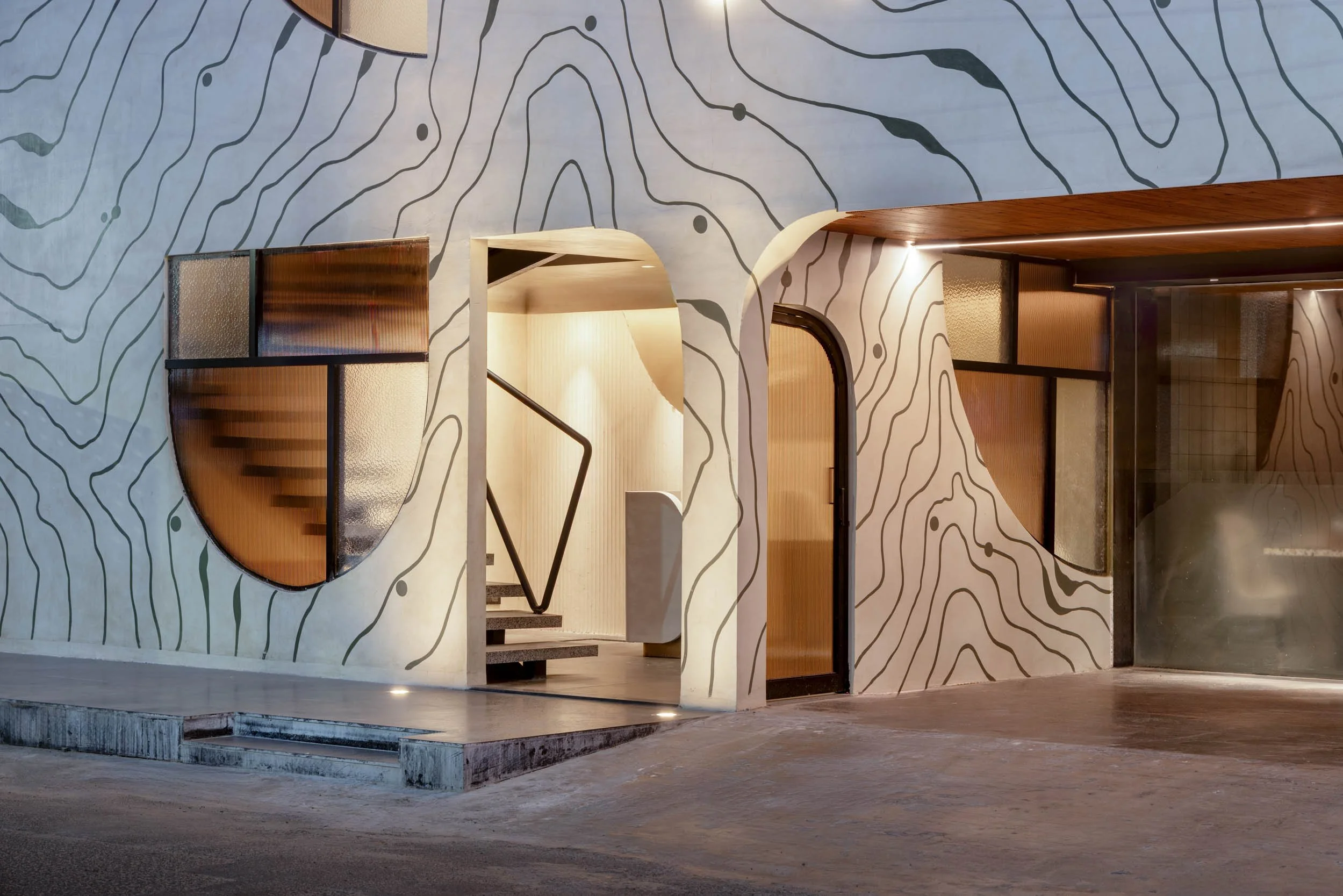 Commercial architectural photography showcasing a modern restaurant entryway, highlighting custom topographical wall textures, archway design, and unique interior architectural details