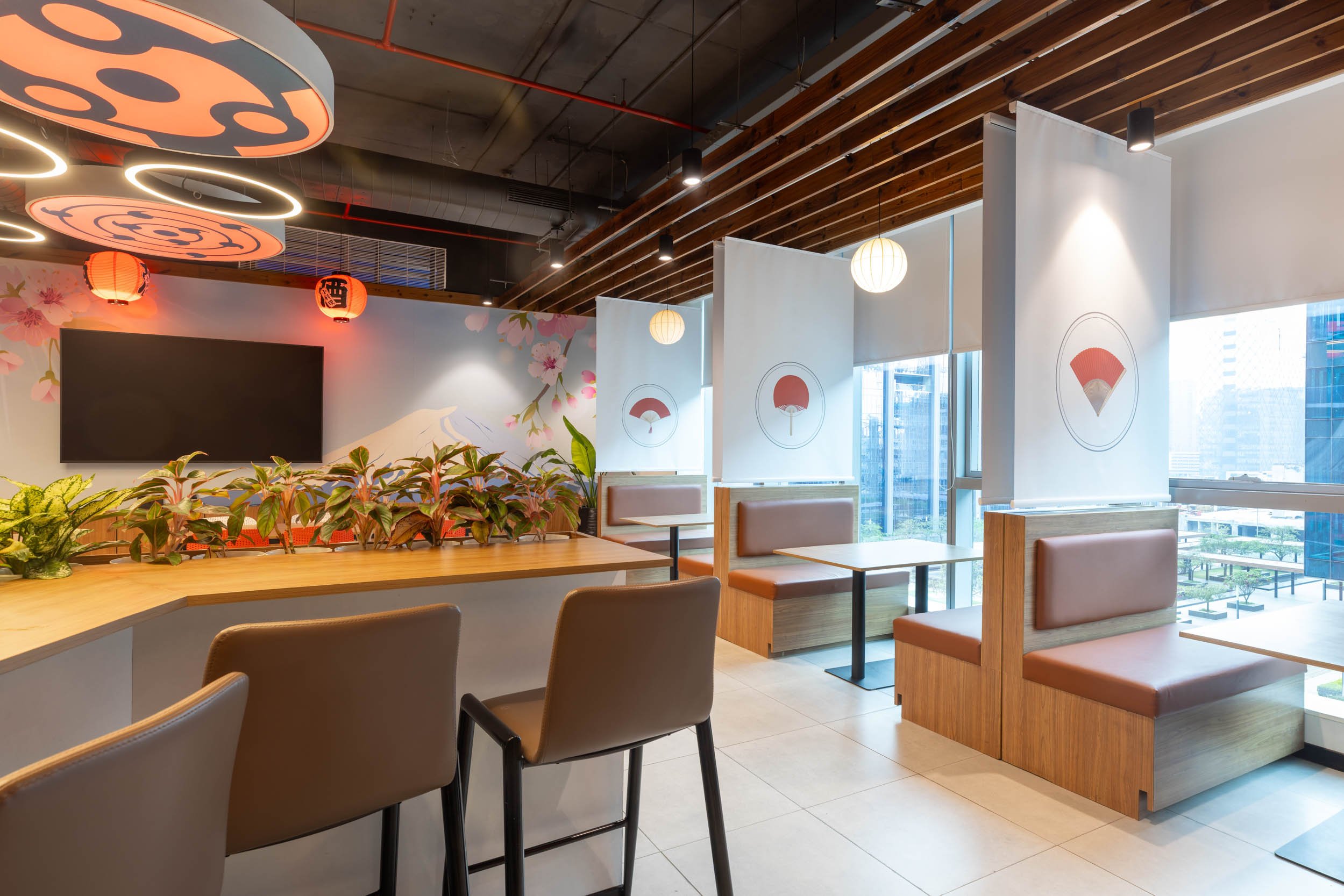 Commercial interior photography showcasing a modern corporate dining and lounge space, highlighting custom architectural lighting, industrial ceiling design, and collaborative breakout areas