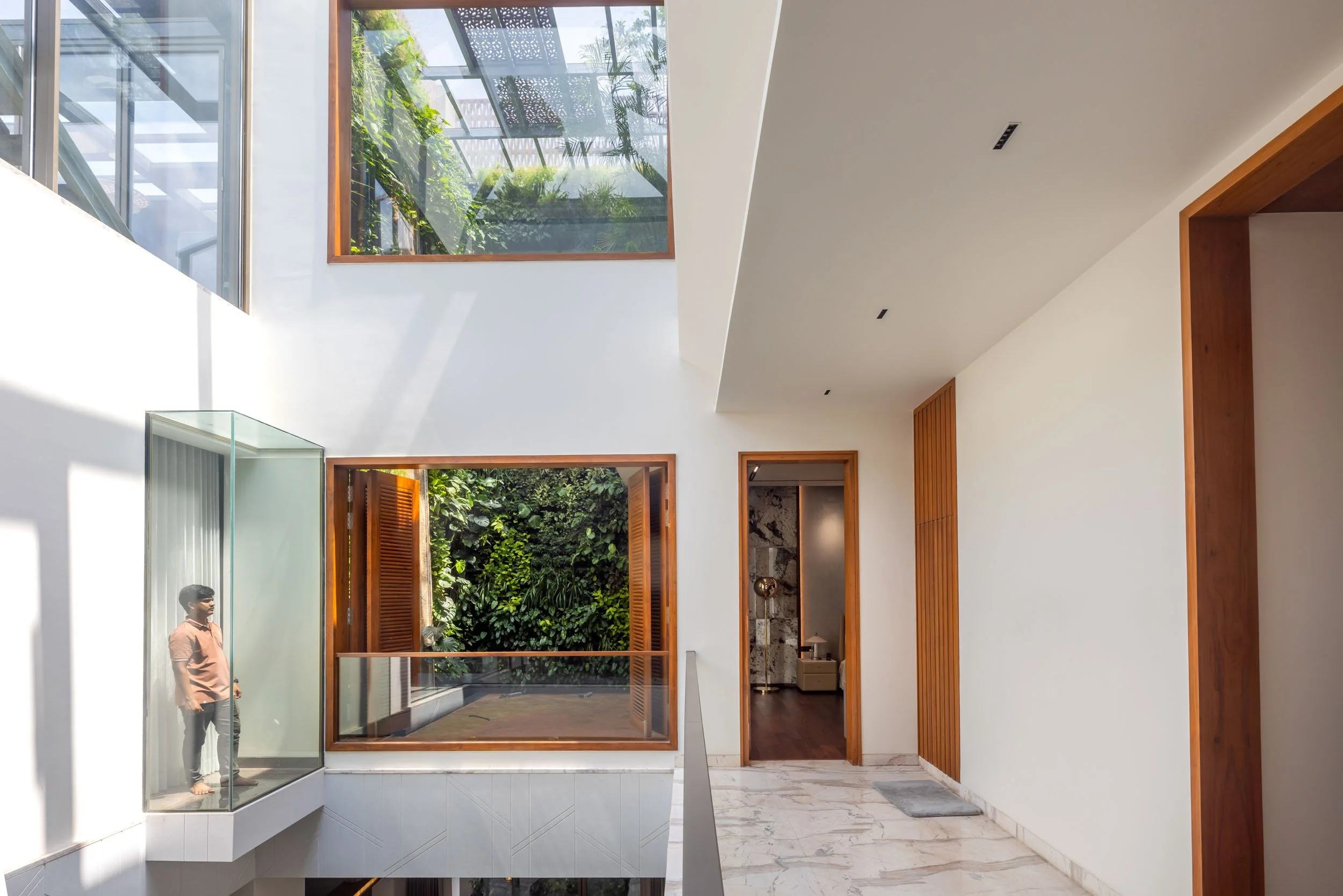 Professional interior architectural photography of a modern residential home, highlighting a bright, multi-level living space with expansive glass windows and a seamless indoor-outdoor connection.