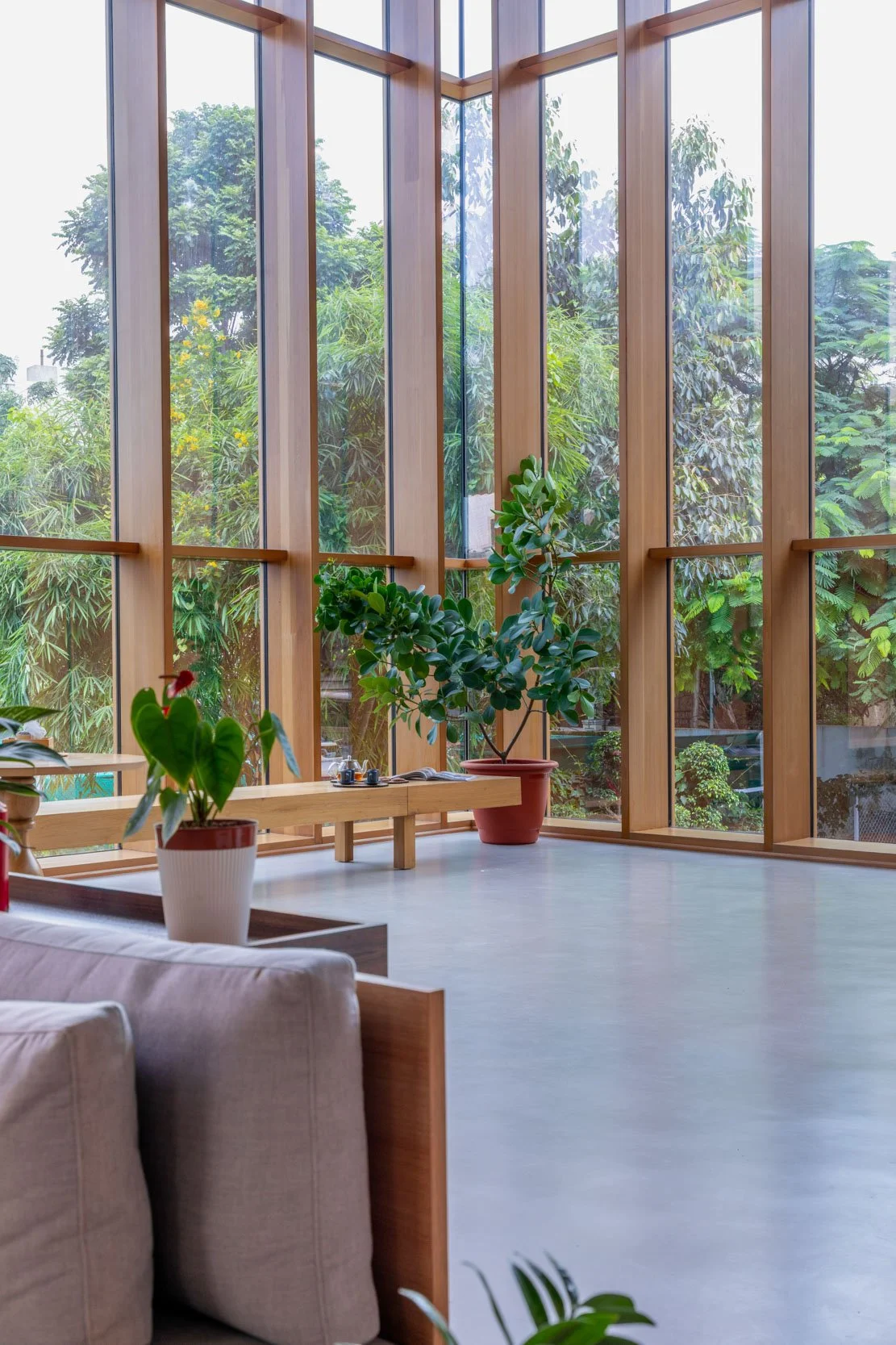 Professional interior architecture photography of a modern commercial lounge, highlighting expansive floor-to-ceiling glass windows with vertical wood framing and abundant natural light