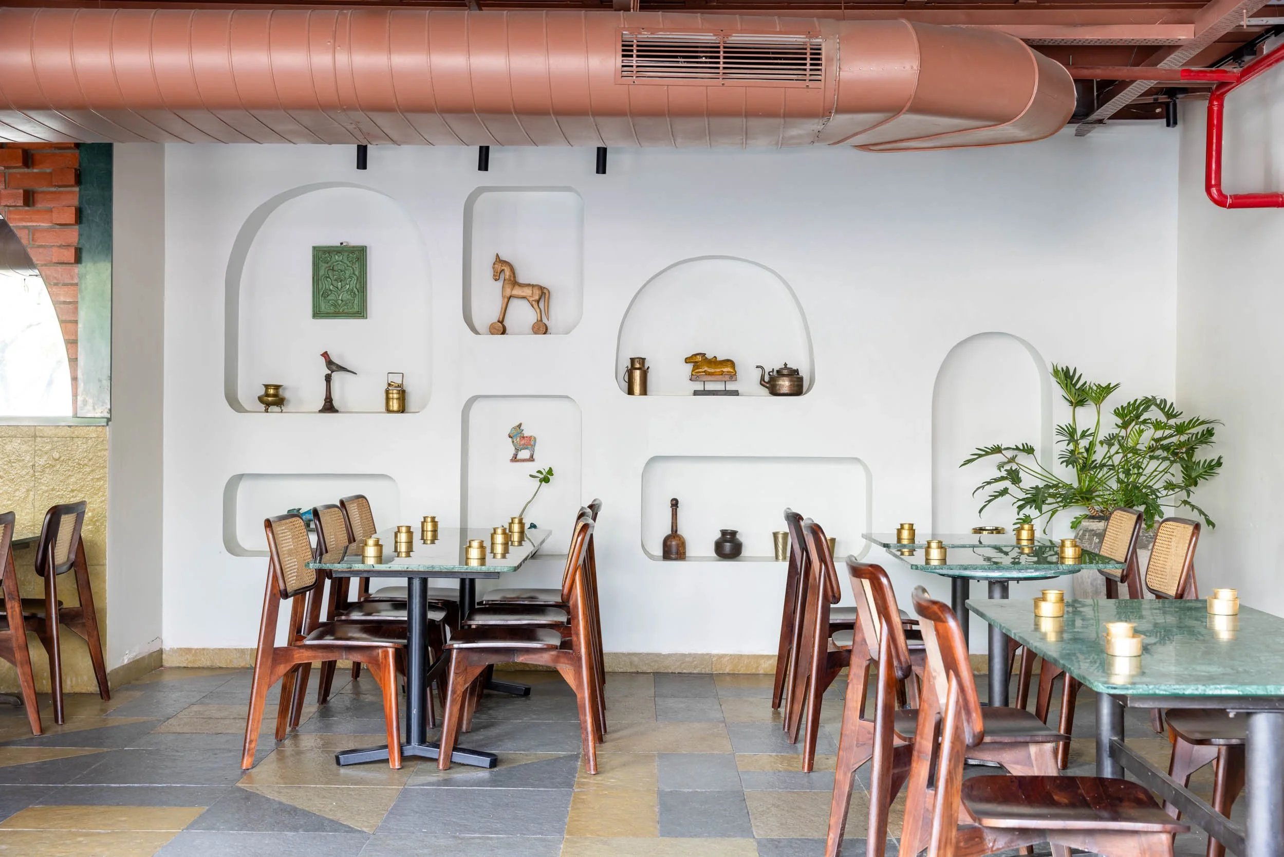 Commercial interior photography showcasing a modern cafe and restaurant design, highlighting custom architectural wall niches, exposed industrial ceiling elements, and inviting hospitality furniture