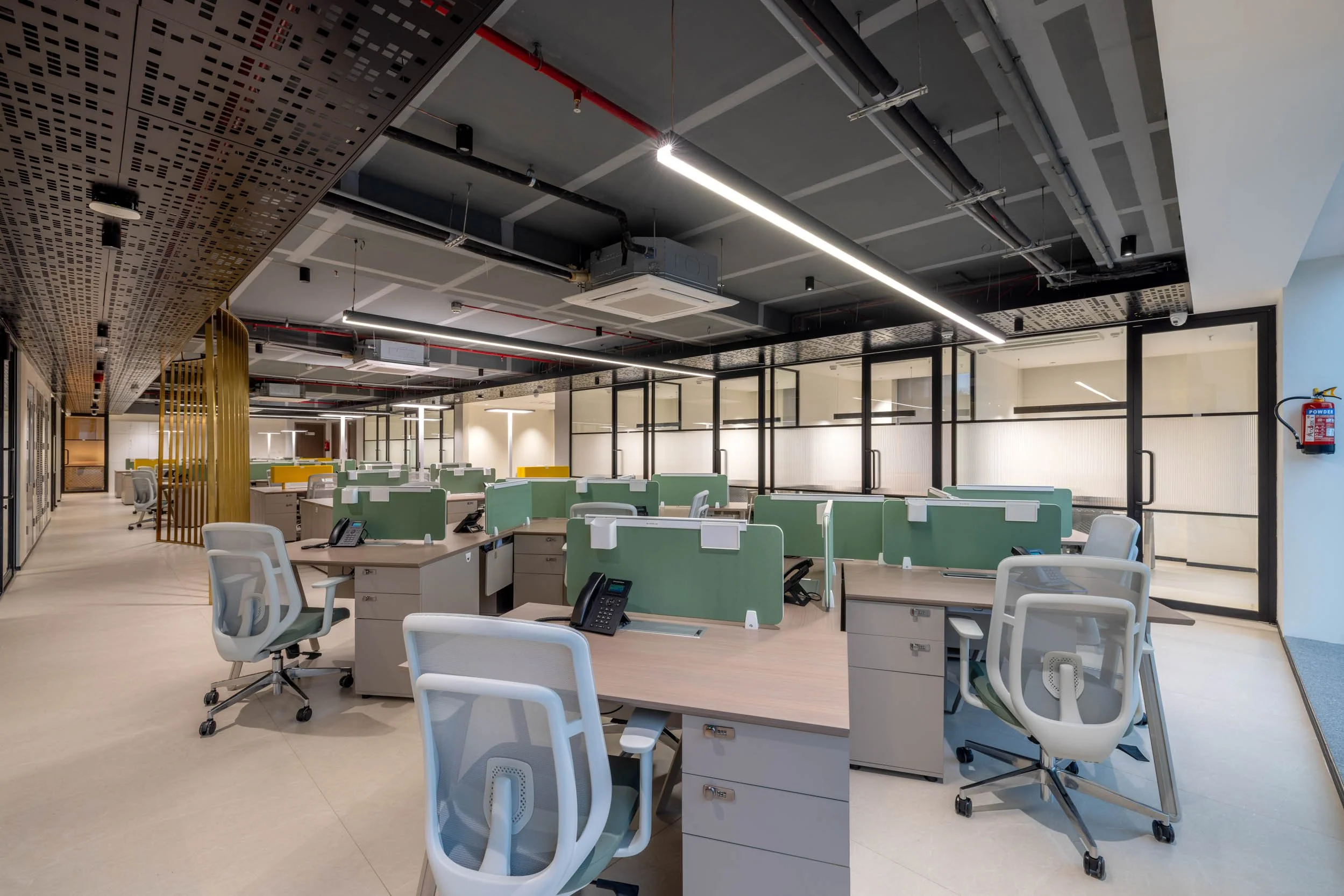 Commercial interior photography showcasing a modern corporate workspace, highlighting open-plan desk arrangements, glass office partitions, and industrial ceiling design