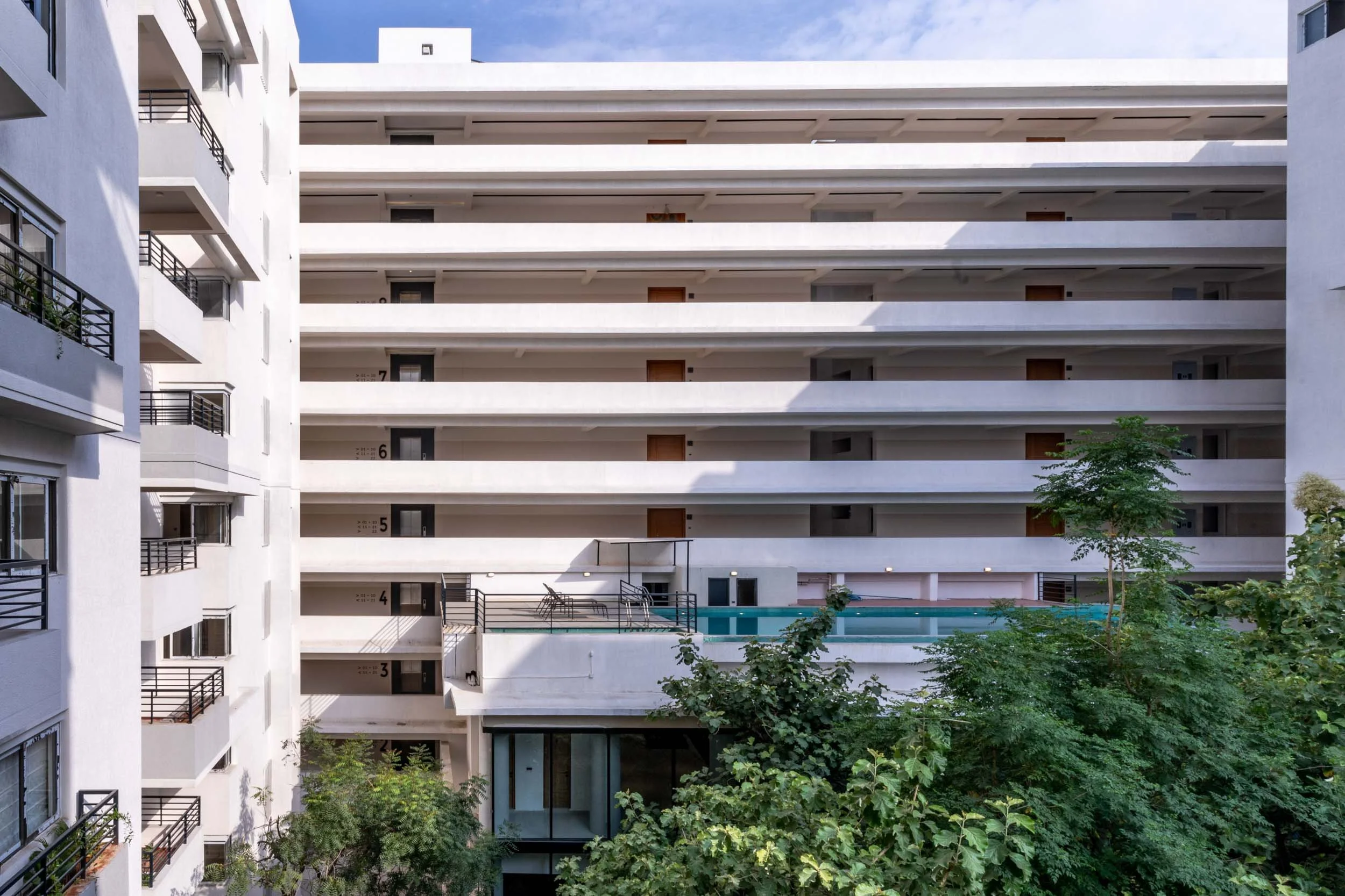 Residential real estate exterior photography showcasing twin modern apartment blocks and integrated green landscaping under a clear blue sky.