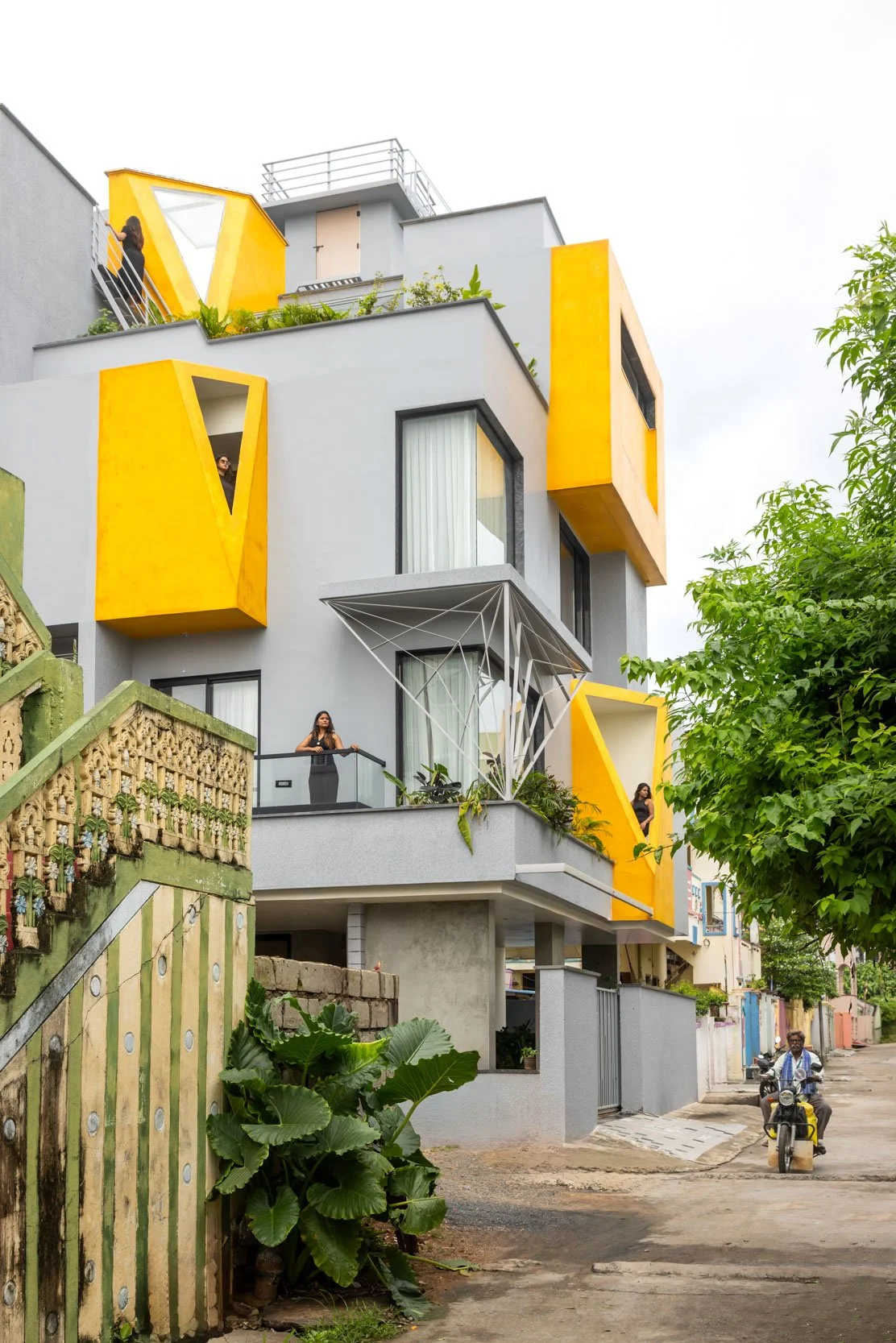 Professional exterior architectural photography of a modern residential home, capturing a vibrant street-level view and highlighting a striking white facade with bold yellow accents.