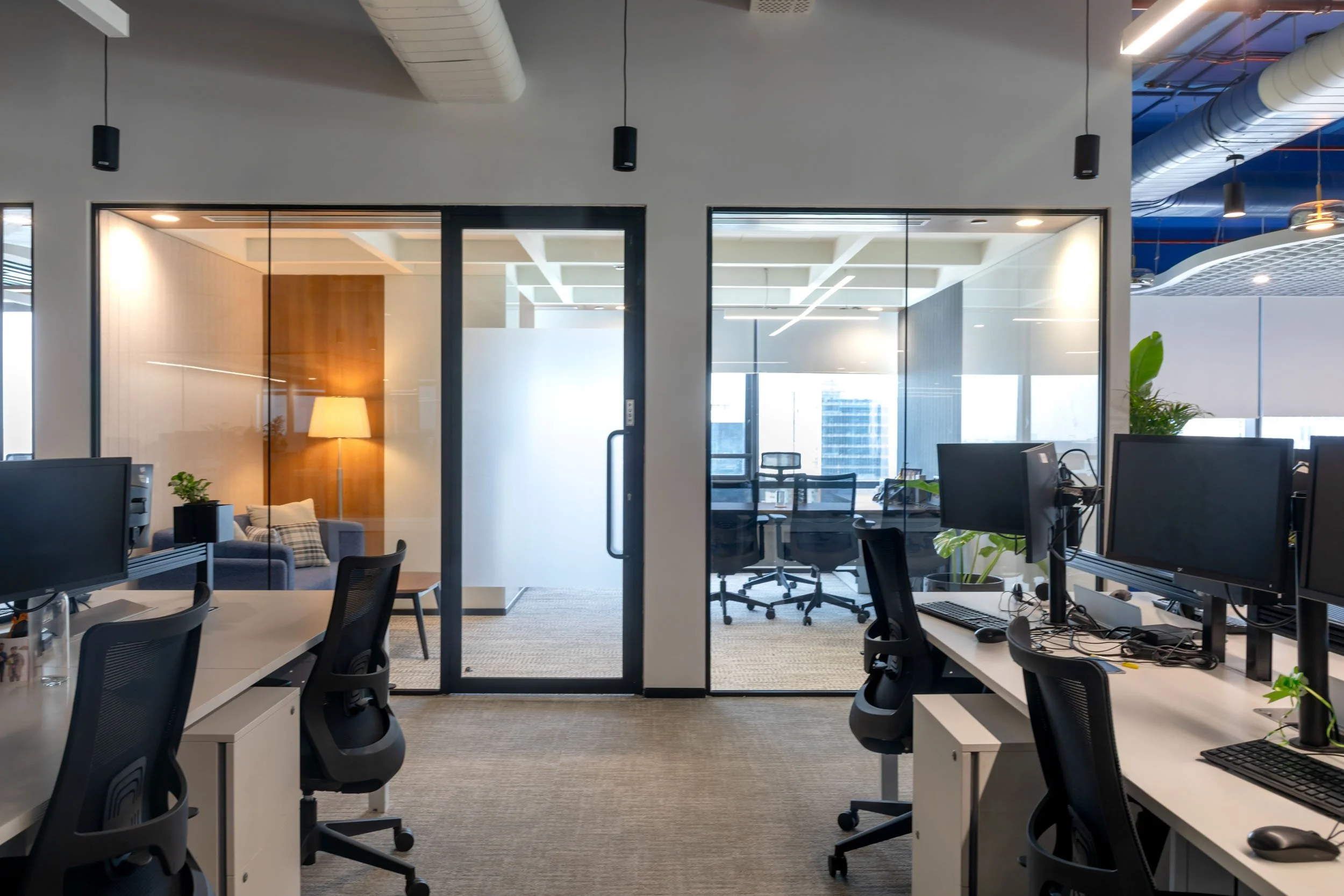 Commercial interior photography showcasing a modern private office design, highlighting black-framed transparent glass partitions, contemporary workspace layouts, and clean architectural lines.