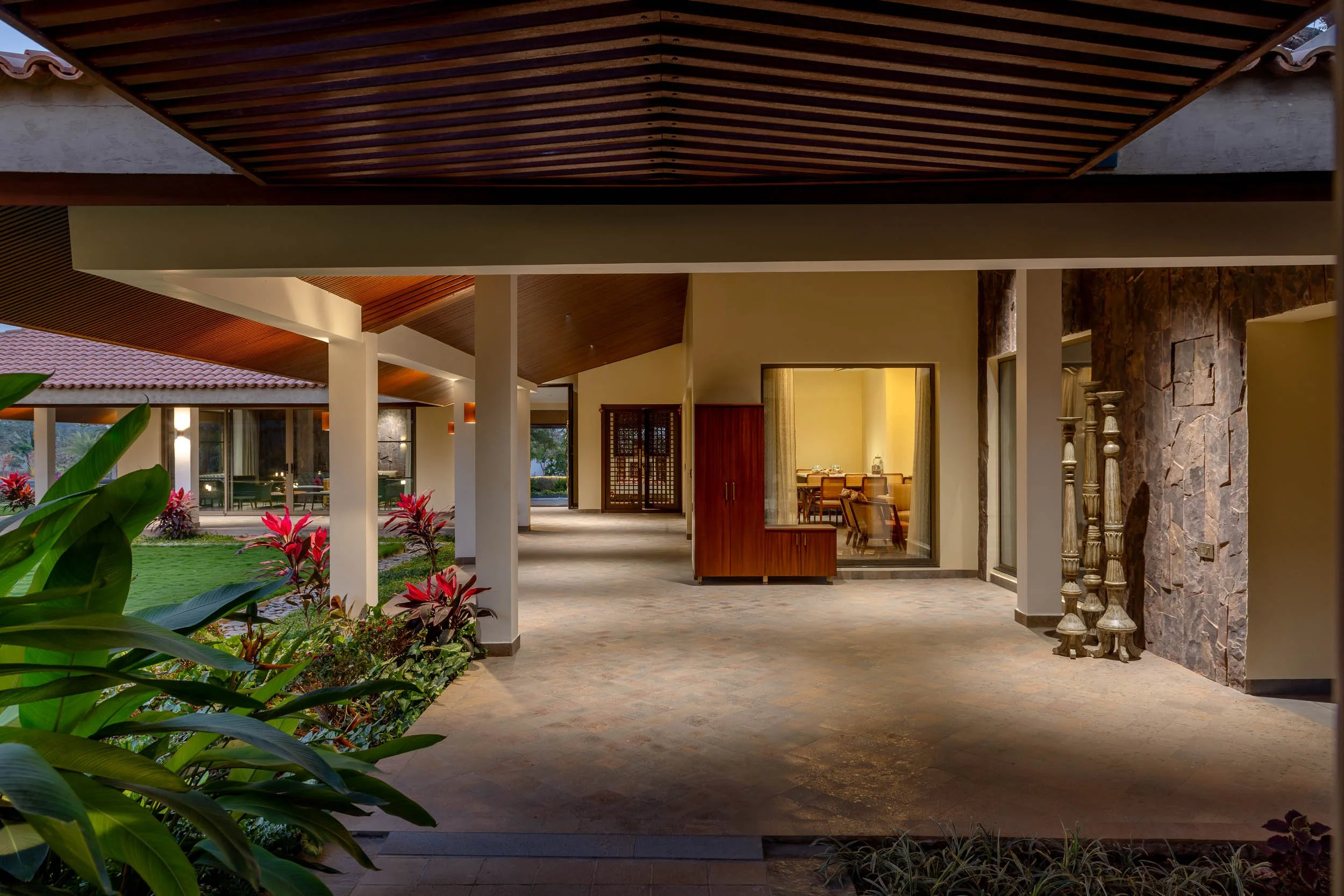 Exterior twilight photography of a luxury resort farm stay featuring a covered stone walkway with a wooden pergola roof and warm ambient lighting.