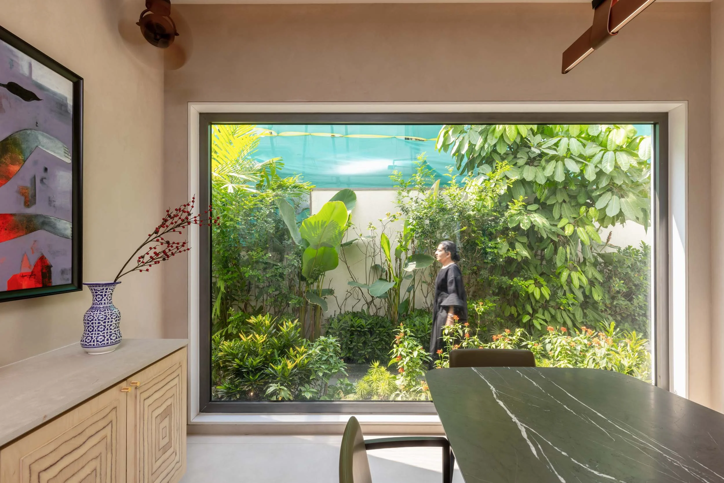 nterior view of a modern dining space featuring a large picture window that overlooks a vibrant tropical garden
