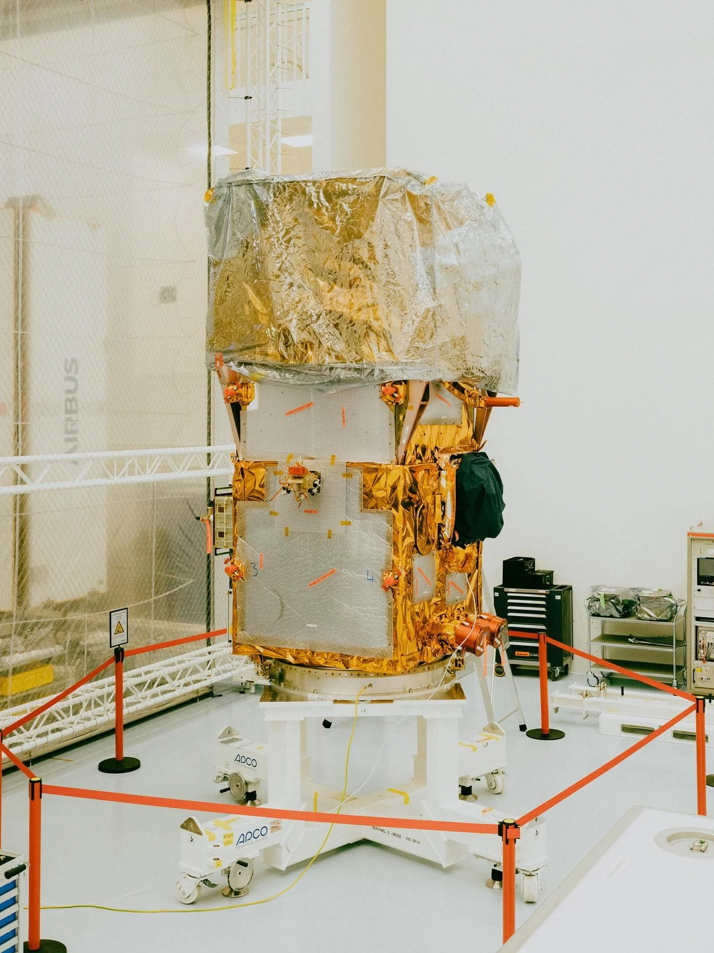 Satellitenmodell im Forschungsraum, umgeben von Absperrungen, Geräte und Kabel