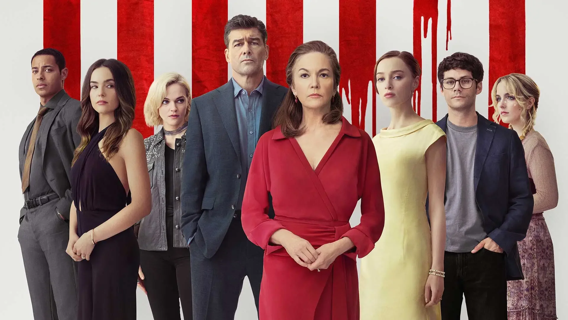 A group of nine diverse people standing together against a white wall with red stripes, one of which has red paint dripping down.