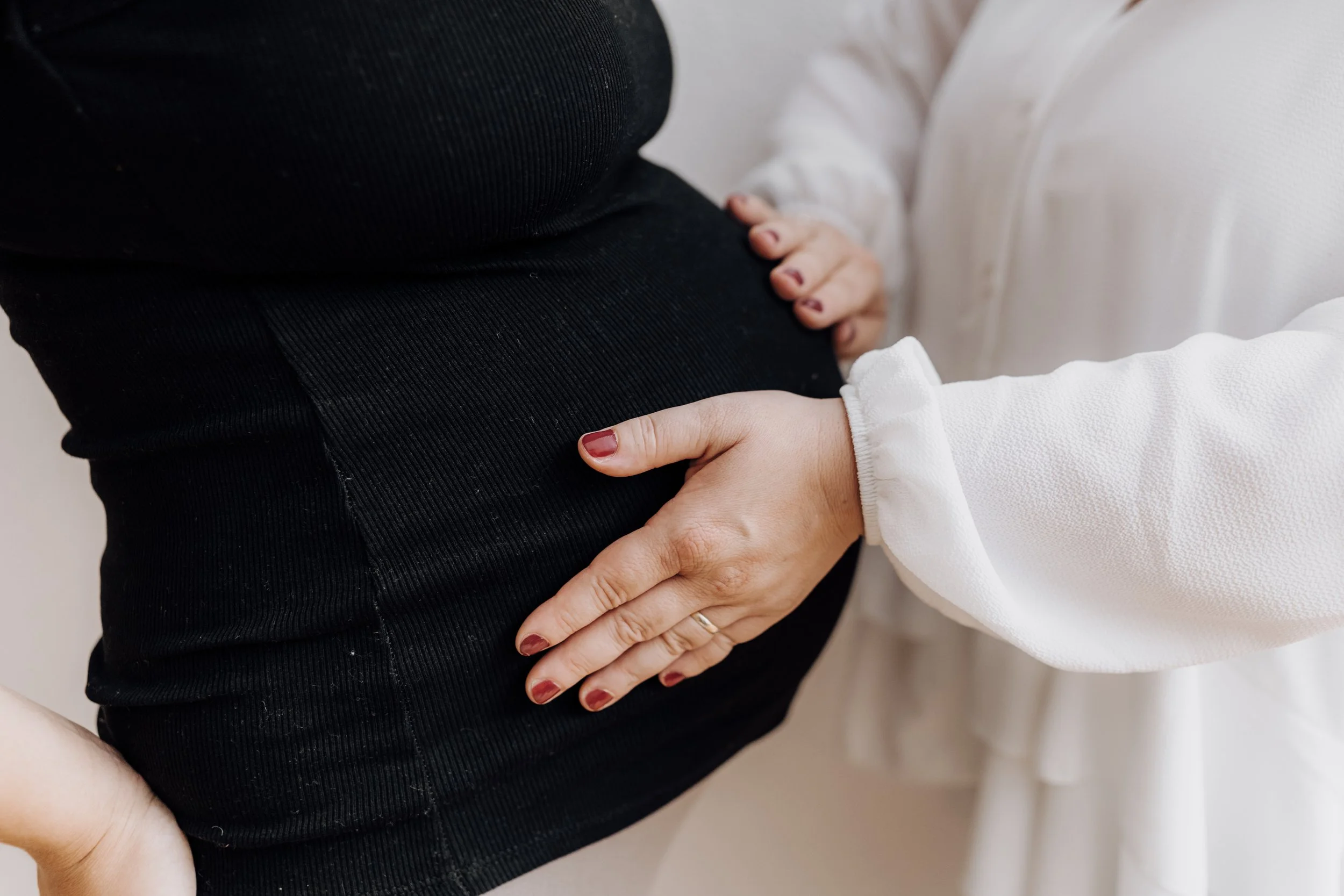 Doula Sonja Stadler legt die Hände liebevoll auf einen Bauch einer schwangeren Frau.