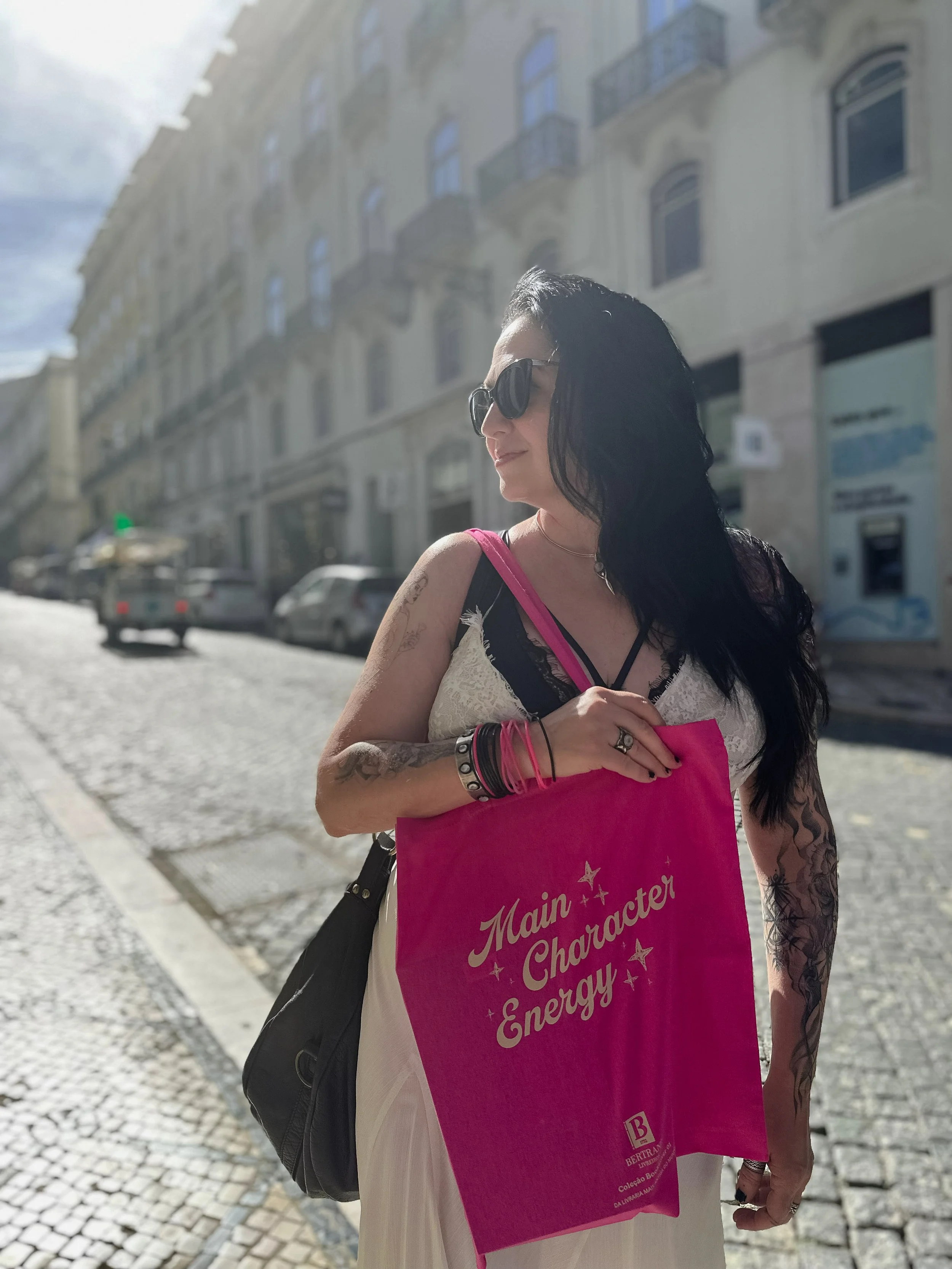 Elisa carrying a "Main Character Energy" tote bag from Bertrand on the streets of Lisbon