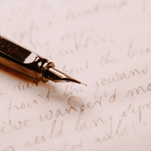 Close up image of a fountain pen and hand writing on a pink paper