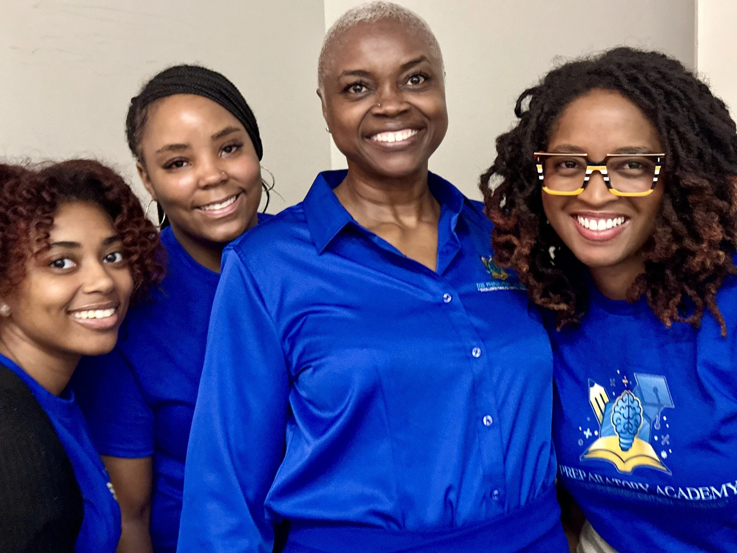 Four African American Women smiling in blue shirts
