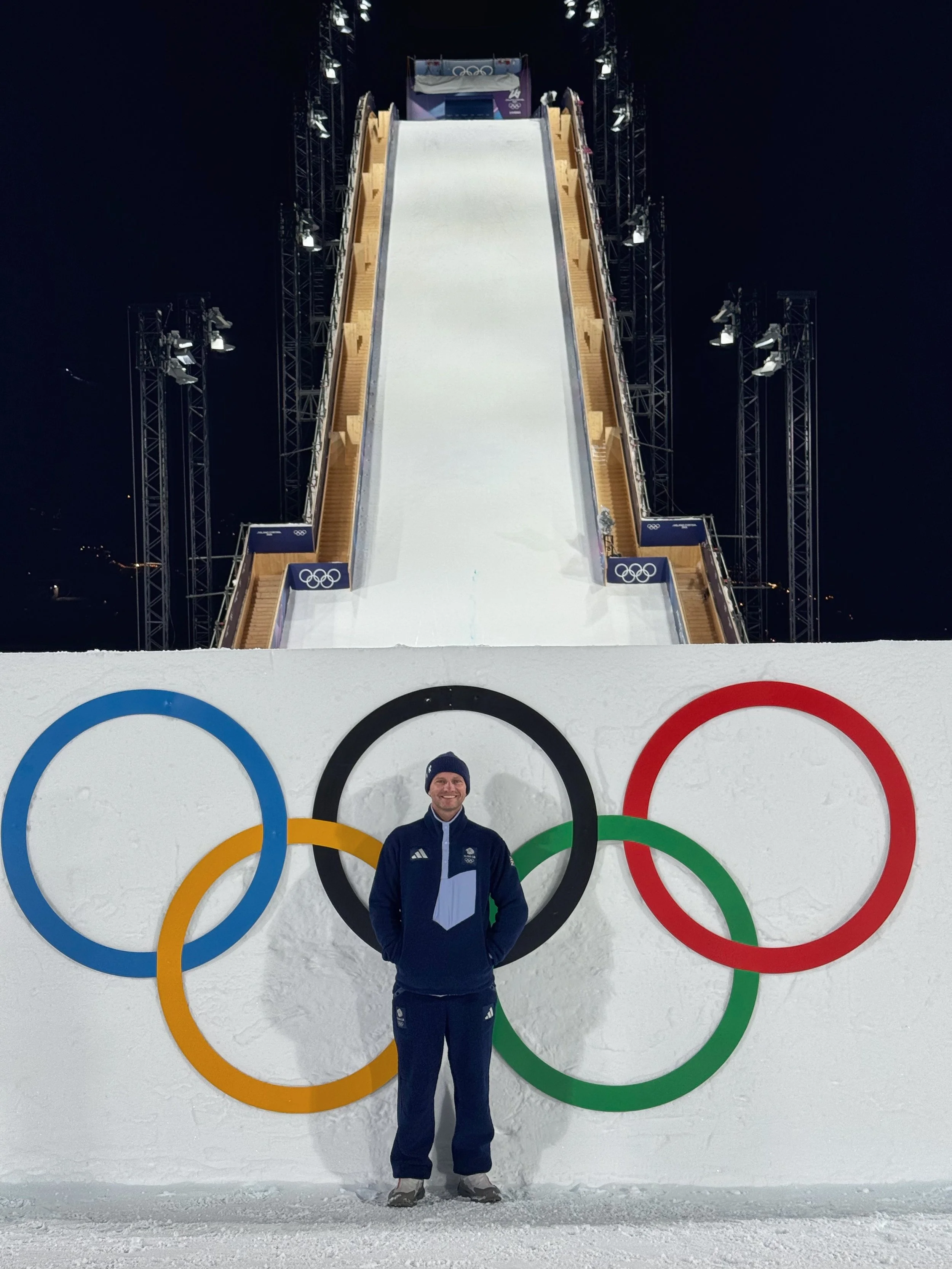 High-performance coach at Olympic big air venue, elite competition environment under pressure