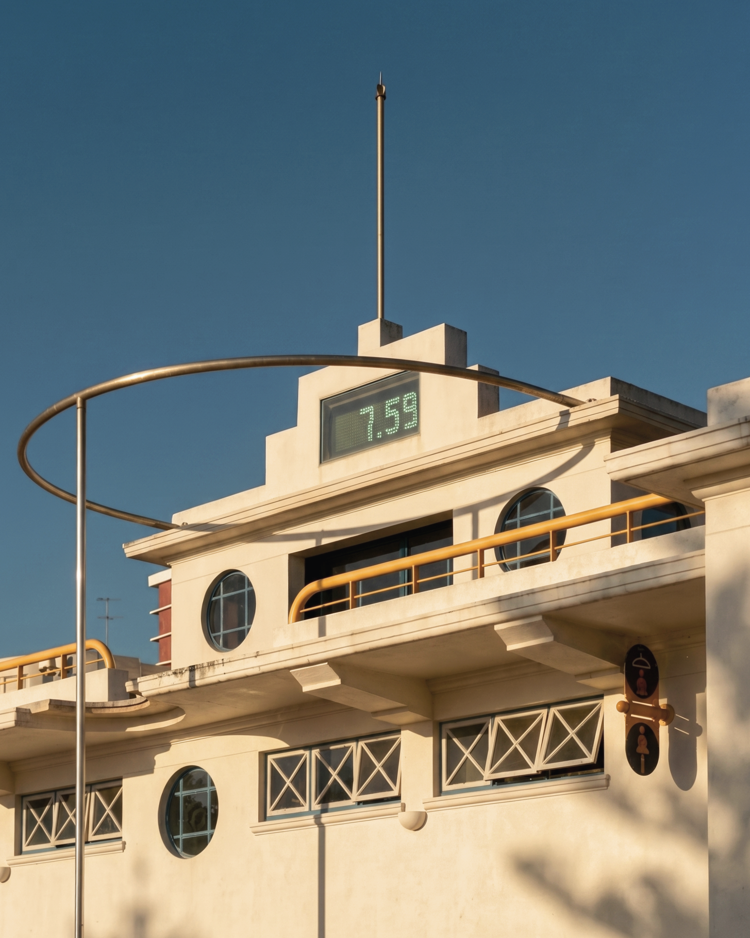 Building with CCTV display showing 7.59 and traffic lights. Clear sky background.