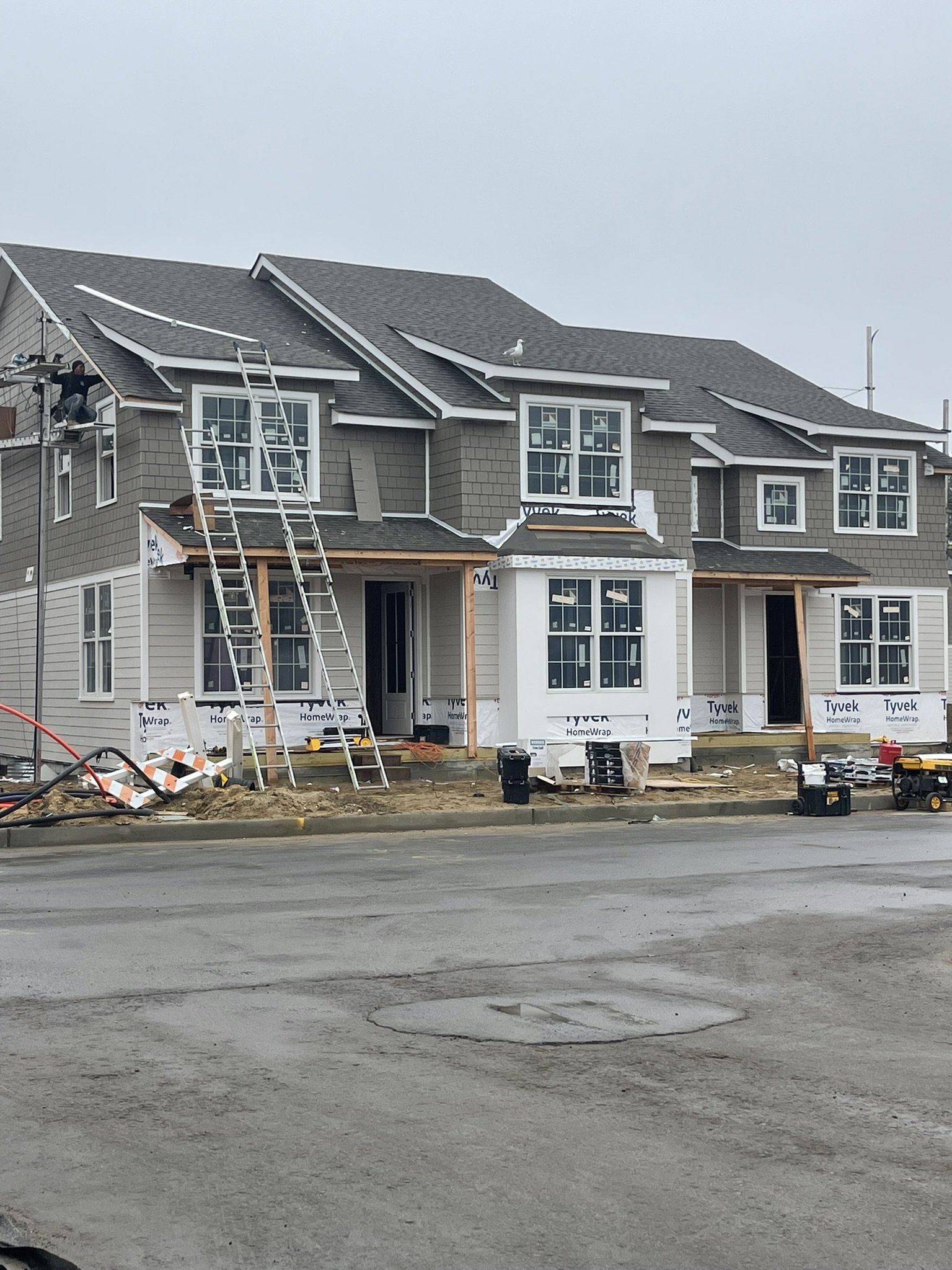 Custom home exterior construction with gray siding, window installation, and residential renovation work in progress by Shore Craft Contracting