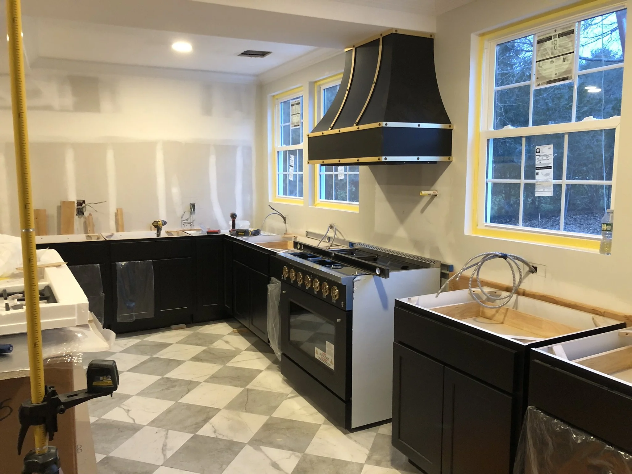Kitchen renovation in progress with custom cabinetry, Calacatta quartz countertops, appliance installation, and finish work underway