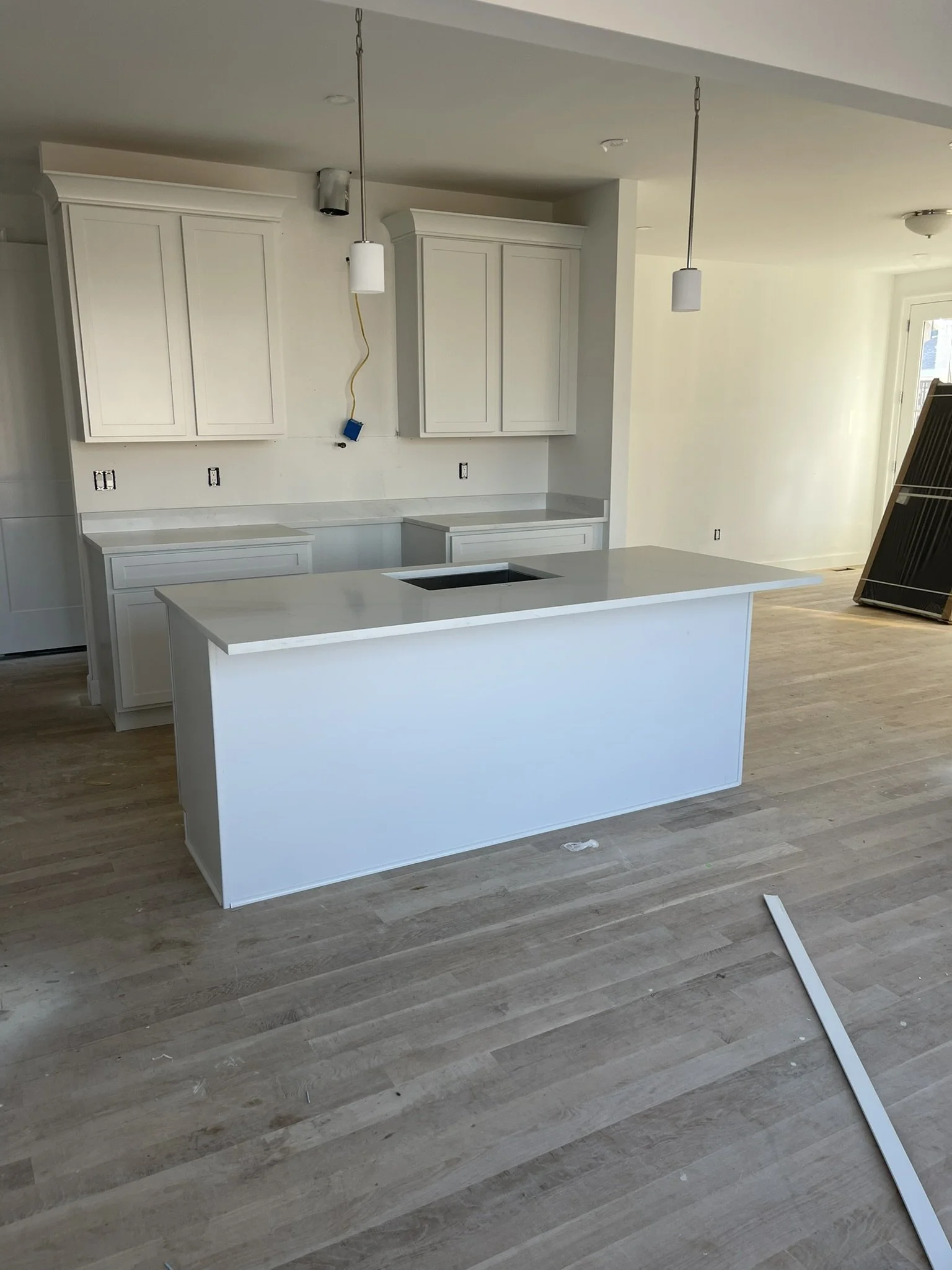 Kitchen remodel in progress with custom cabinetry, Calacatta quartz countertops, island cooktop, pendant lights, and hardwood flooring