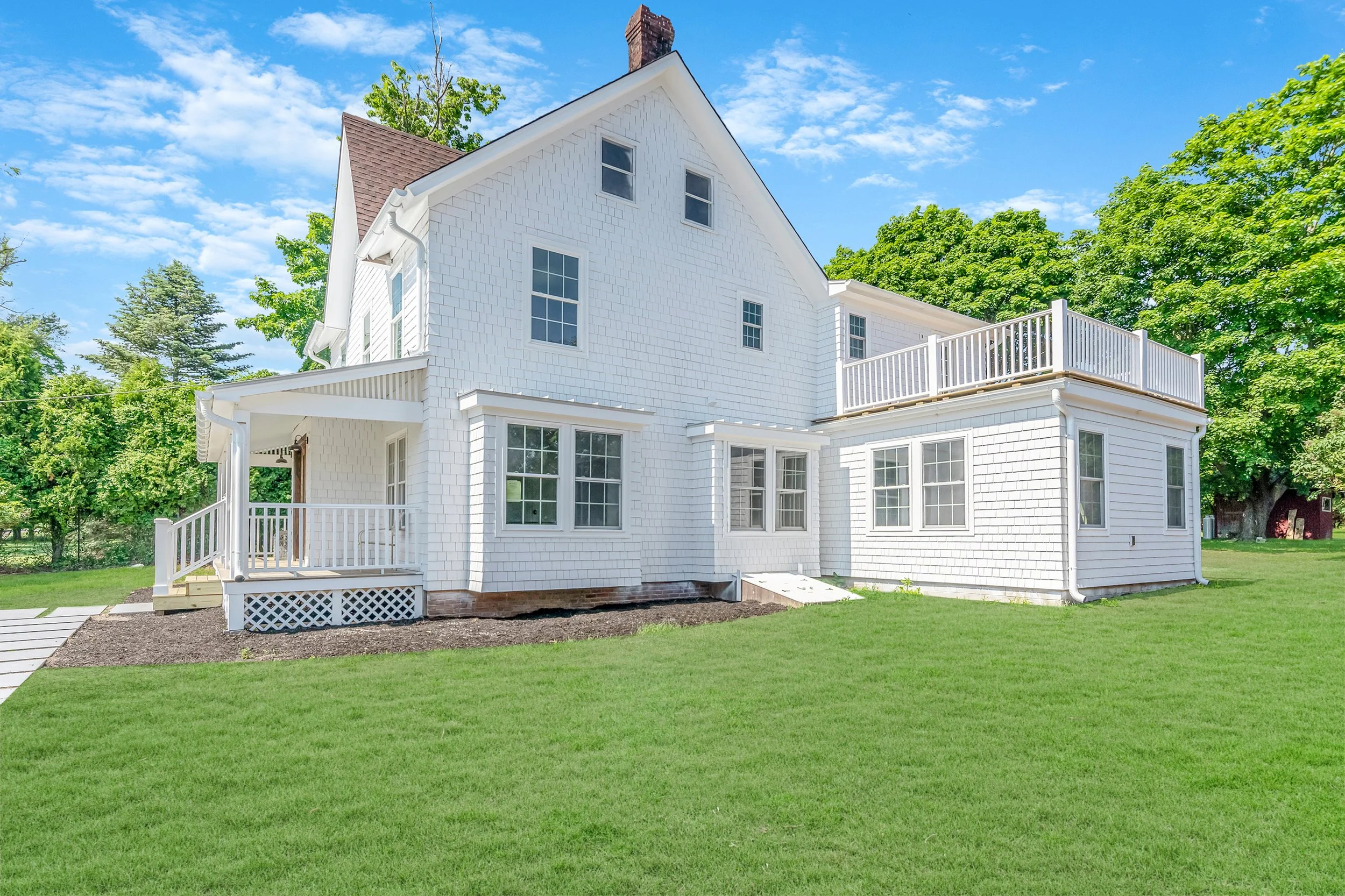 Completed residential exterior renovation with Western Red Cedar shake, rear deck, green lawn, and landscaped backyard