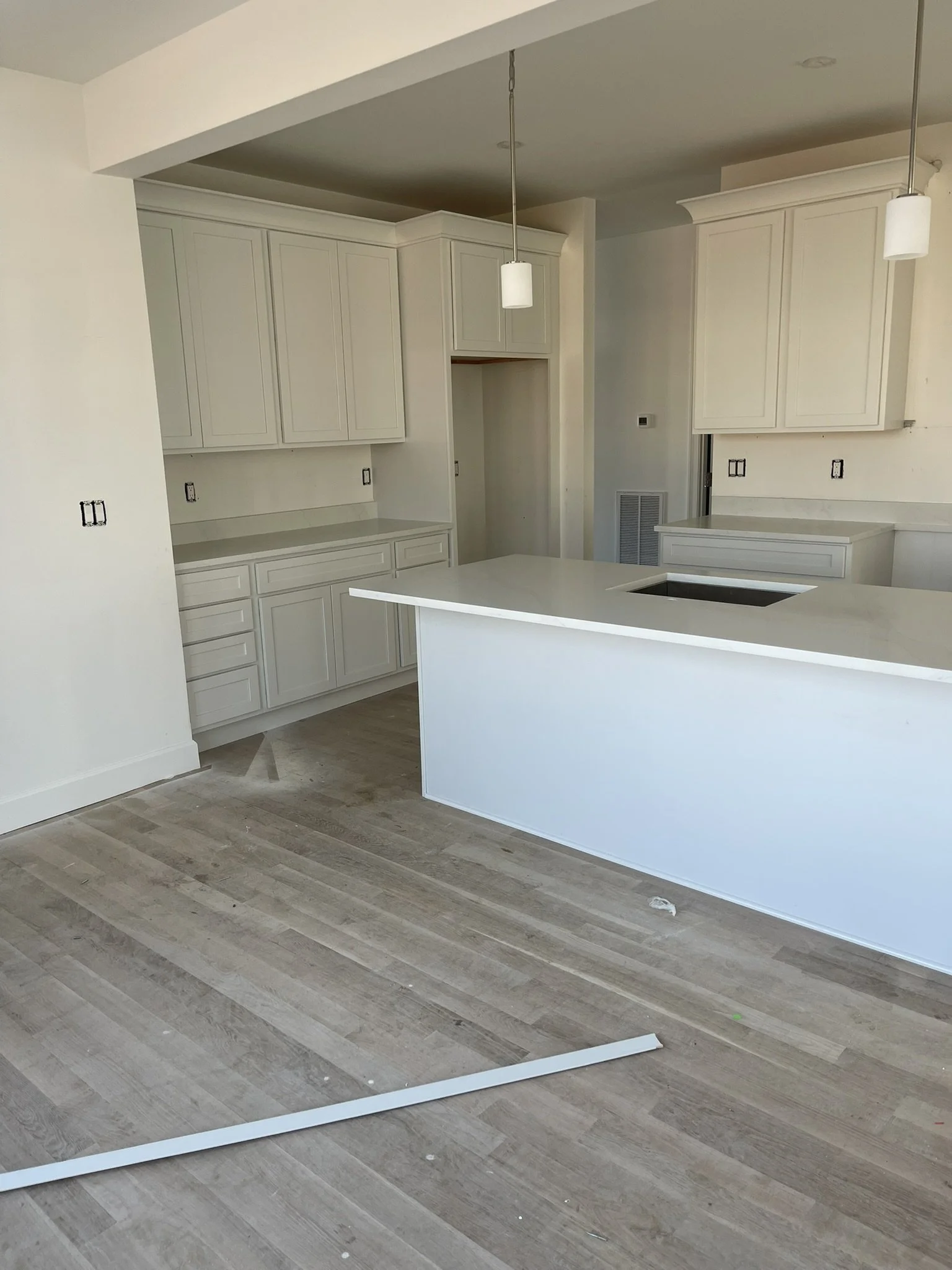 Custom kitchen renovation with white cabinetry, Calacatta quartz countertops, island cooktop, pendant lighting, and hardwood flooring