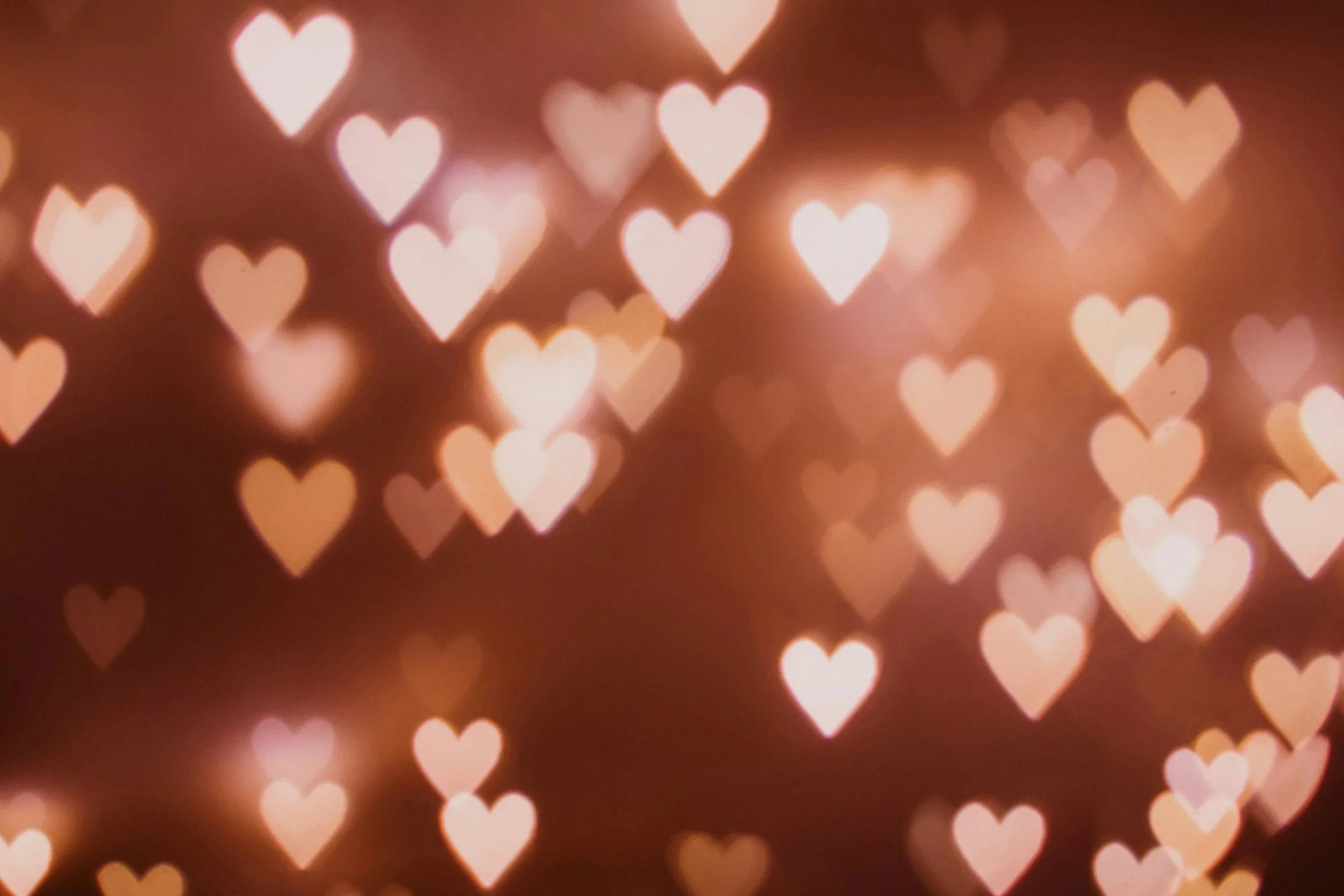 Blurred background with glowing pink and white heart-shaped lights creating a romantic and dreamy atmosphere.