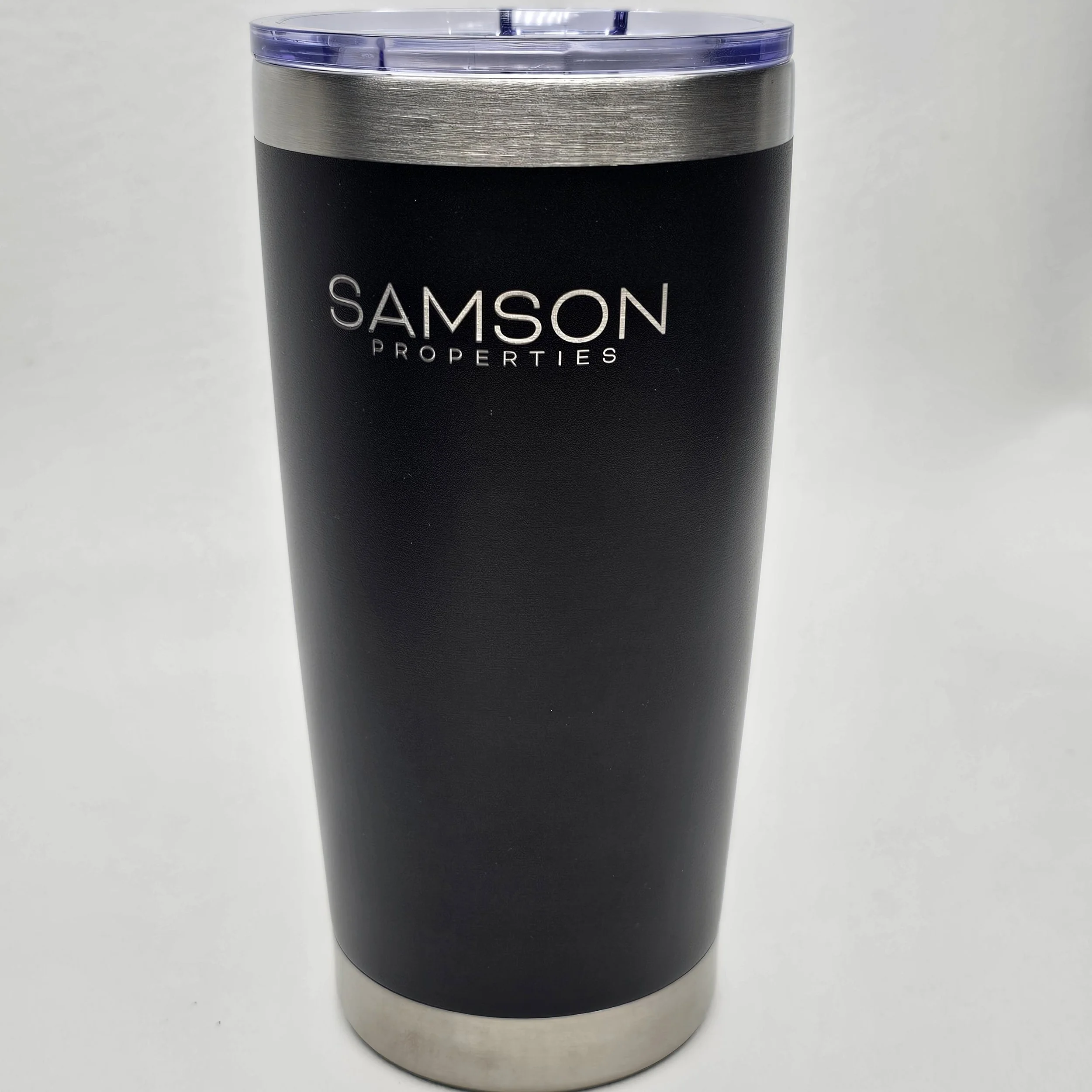 Black travel tumbler with a silver bottom and a purple lid, labeled 'SAMSON PROPERTIES' in silver text.