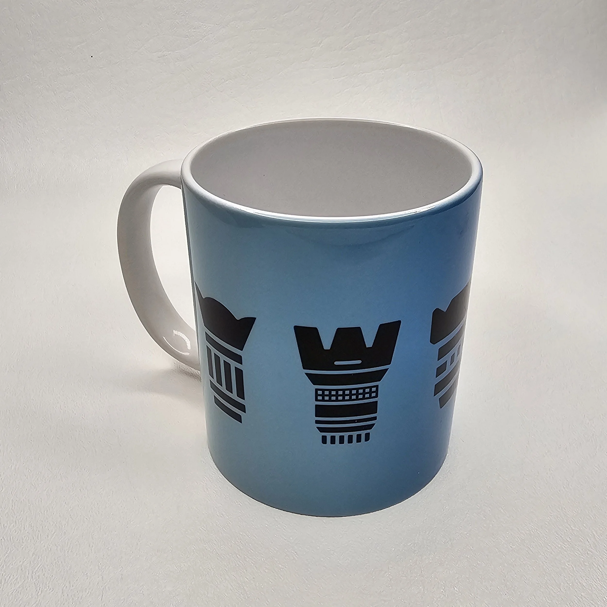 Light blue mug with black African tribal patterns on a white surface.