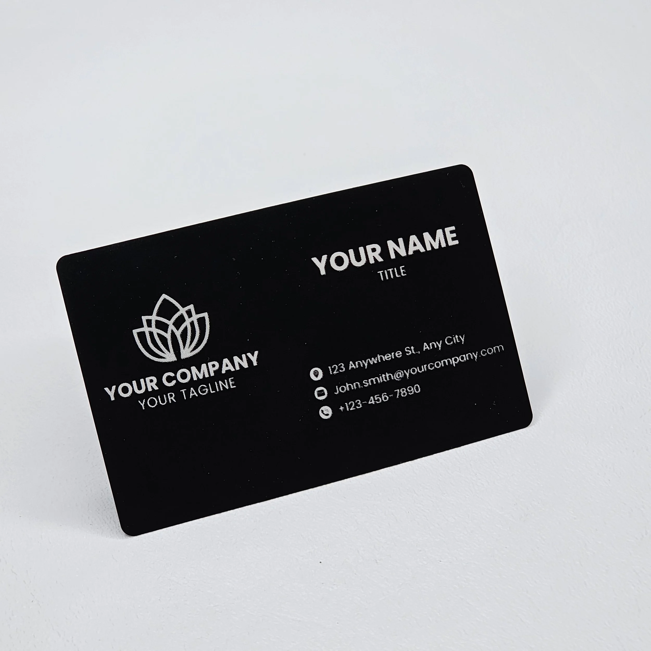 Black business card with white text and logo, displaying company name, tagline, and contact information on a light background.