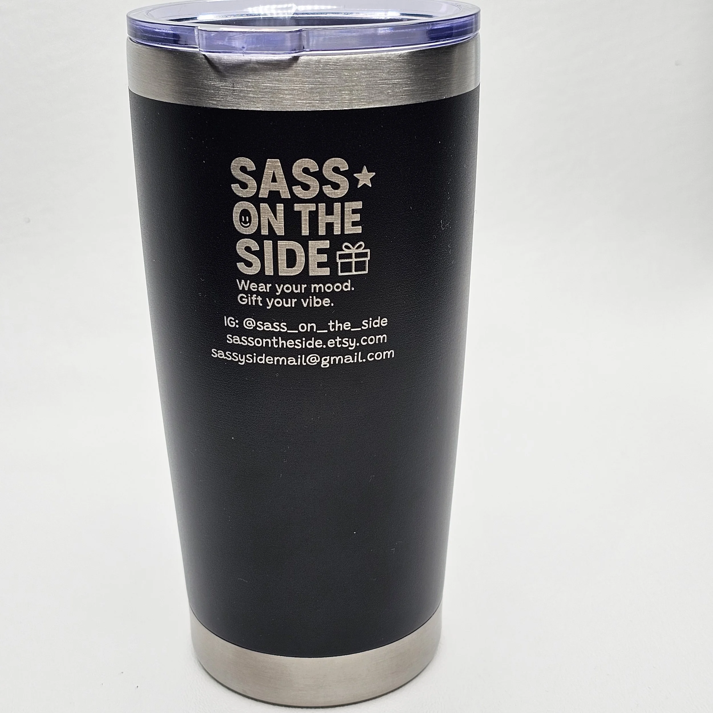 Black travel tumbler with silver top and bottom, branding for SASS ON THE SIDE, featuring white text and icons, including Instagram handle, Etsy shop, and email address.