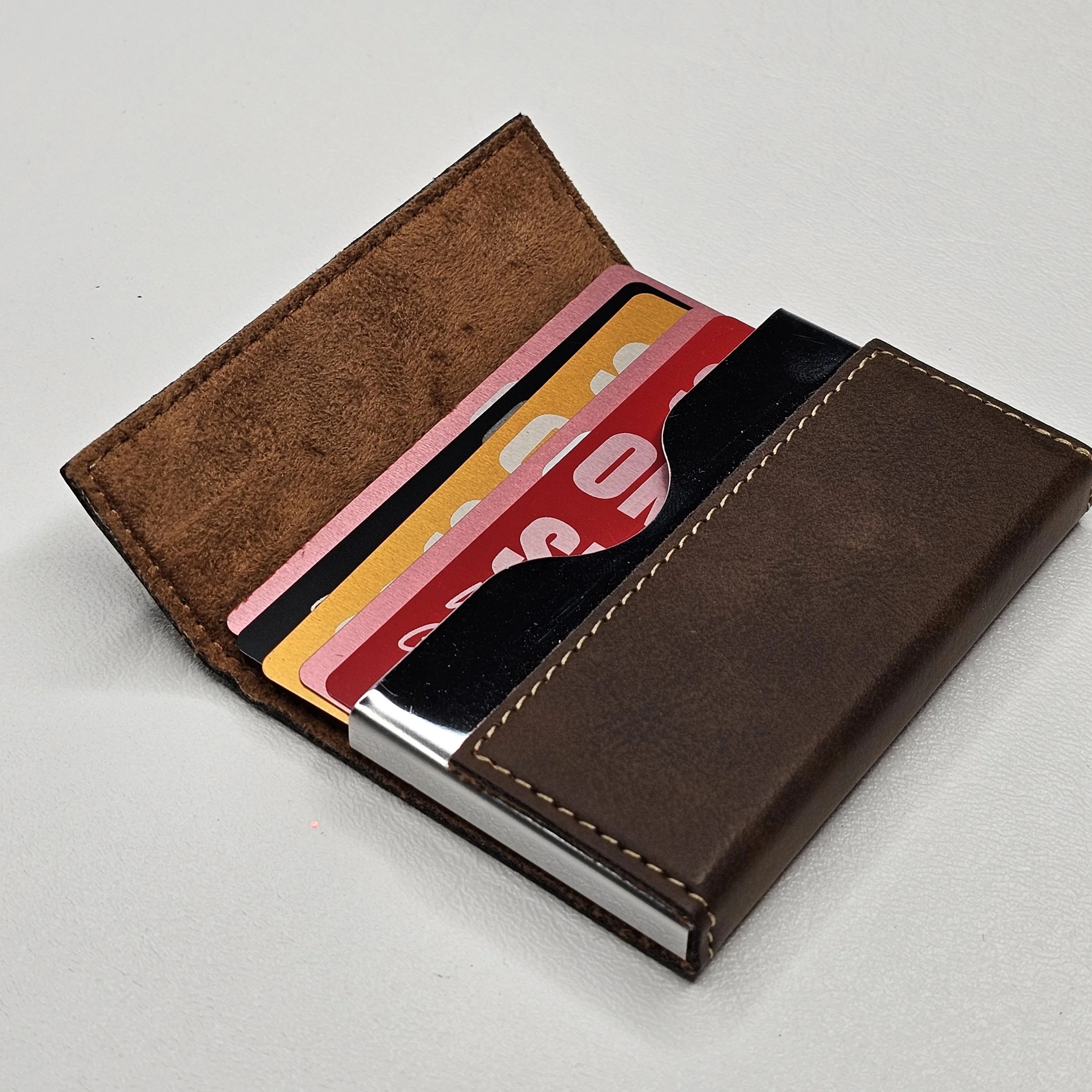 A brown leather wallet containing various credit and debit cards with colorful designs, placed on a white surface.
