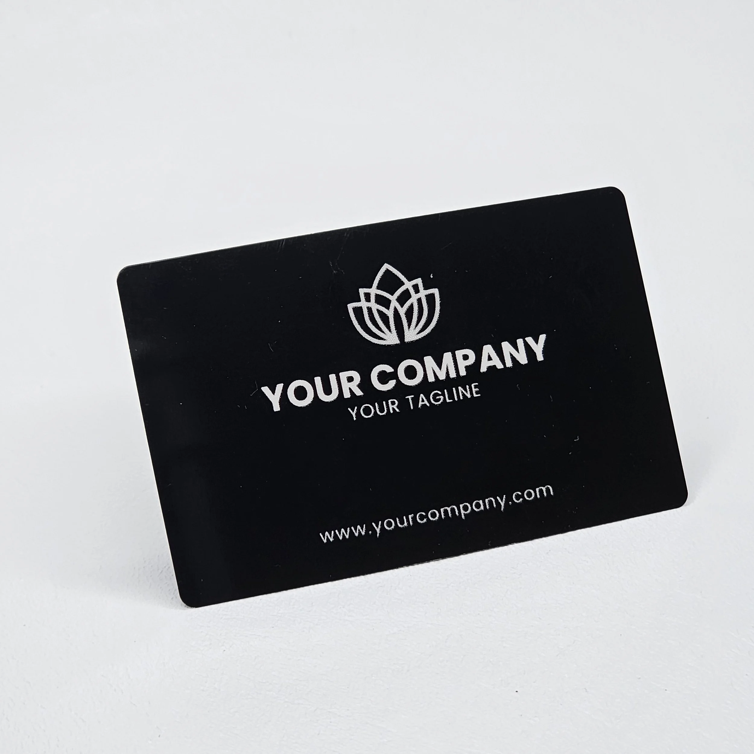 Black business card with a white lotus flower logo, placeholder text 'YOUR COMPANY' and 'YOUR TAGLINE,' and a website URL 'www.yourcompany.com'.