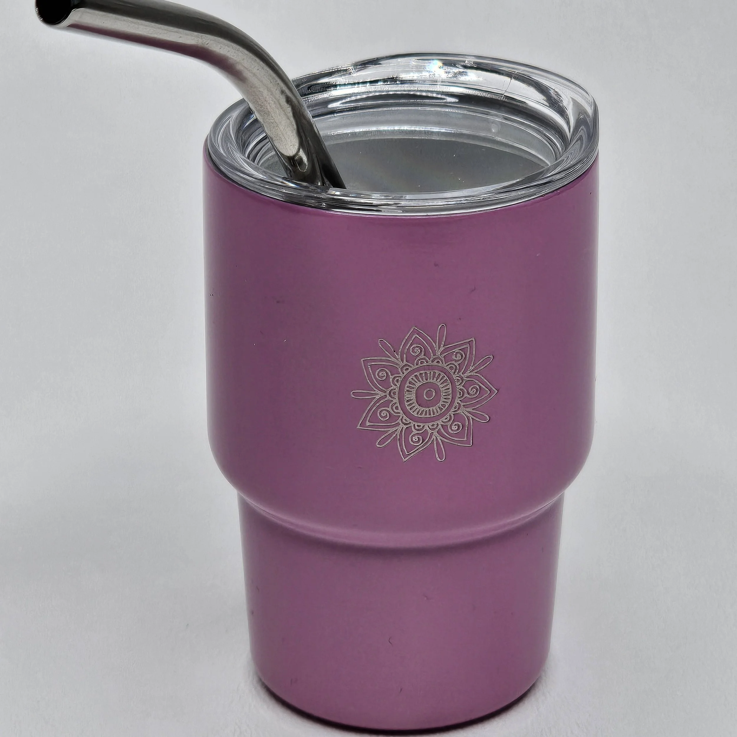 Pink insulated tumbler with a clear lid and metal straw, featuring a decorative floral design on the front.