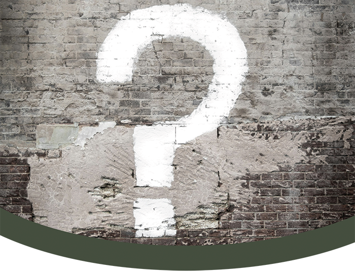 White question mark painted on a weathered brick wall.