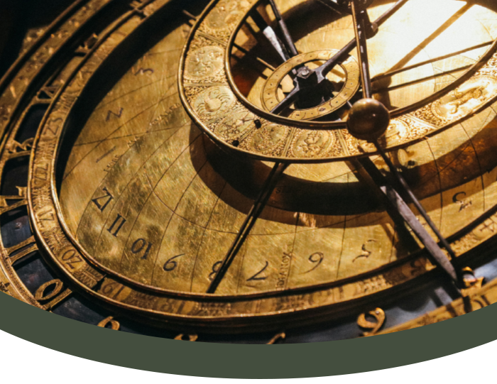 Close-up of an antique clock face with Roman and Arabic numerals, gold details, and clock hands.