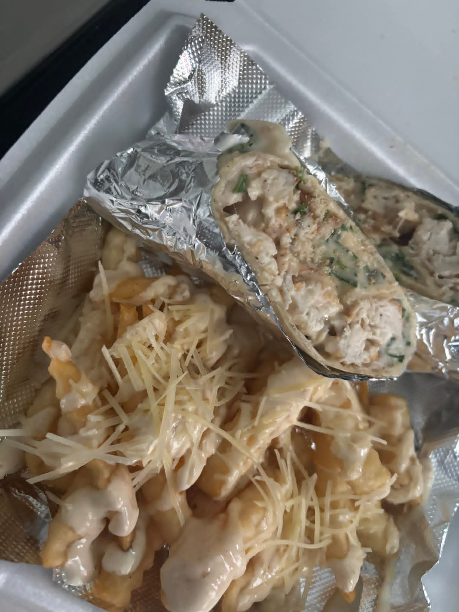 Fried chicken coated with cheese, pasta with creamy sauce, and a partially opened foil-wrapped stuffed chicken breast with herbs