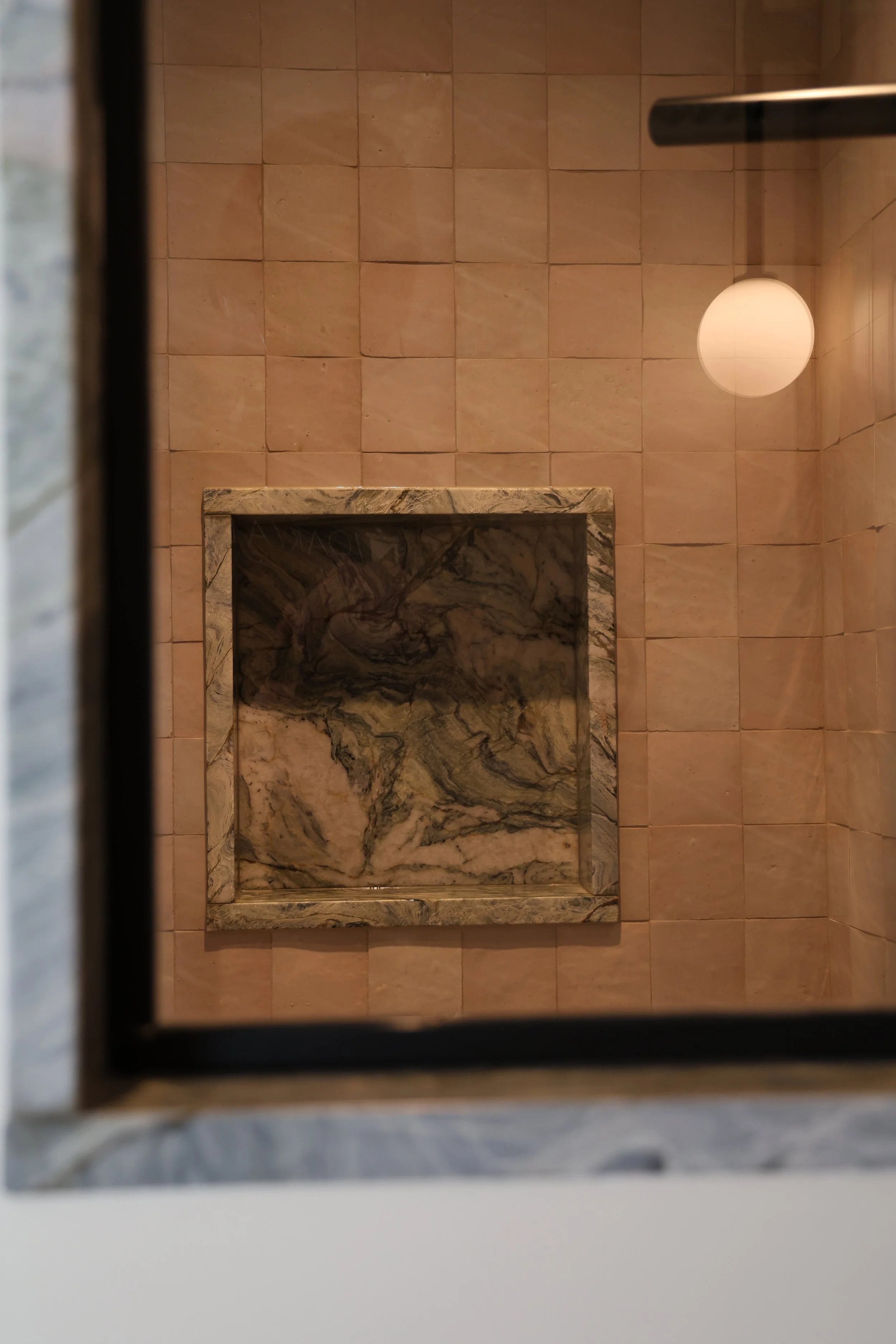 View of a tiled bathroom floor from above, featuring a granite counter with a marbled pattern.