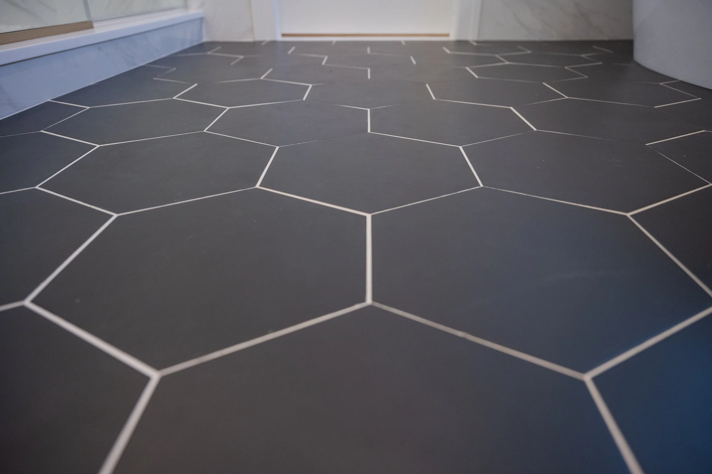 Close-up of a black floor with white hexagon and irregular shaped tile outlines.