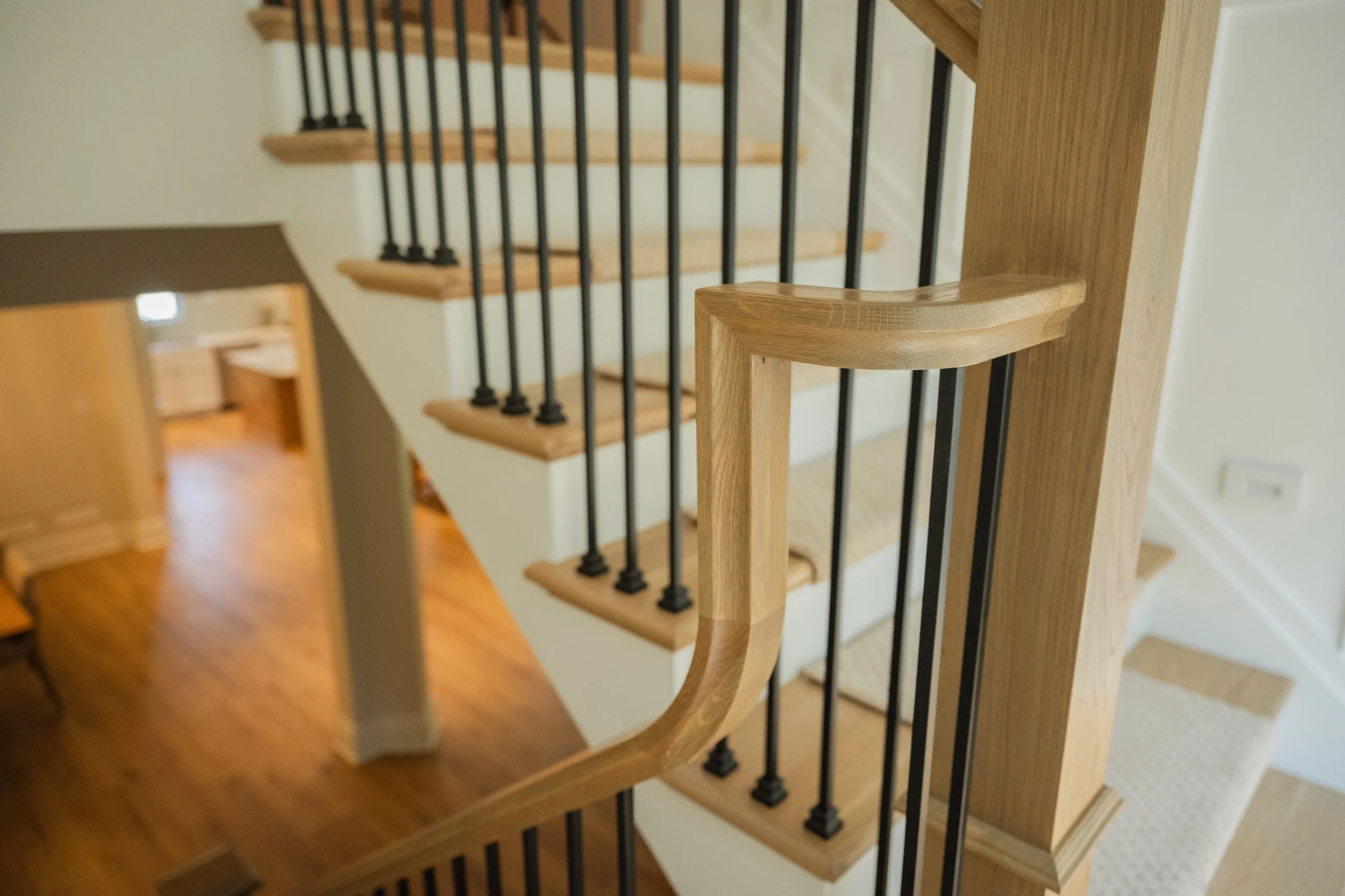 Wooden staircase with black metal balusters, viewed from the top looking down.
