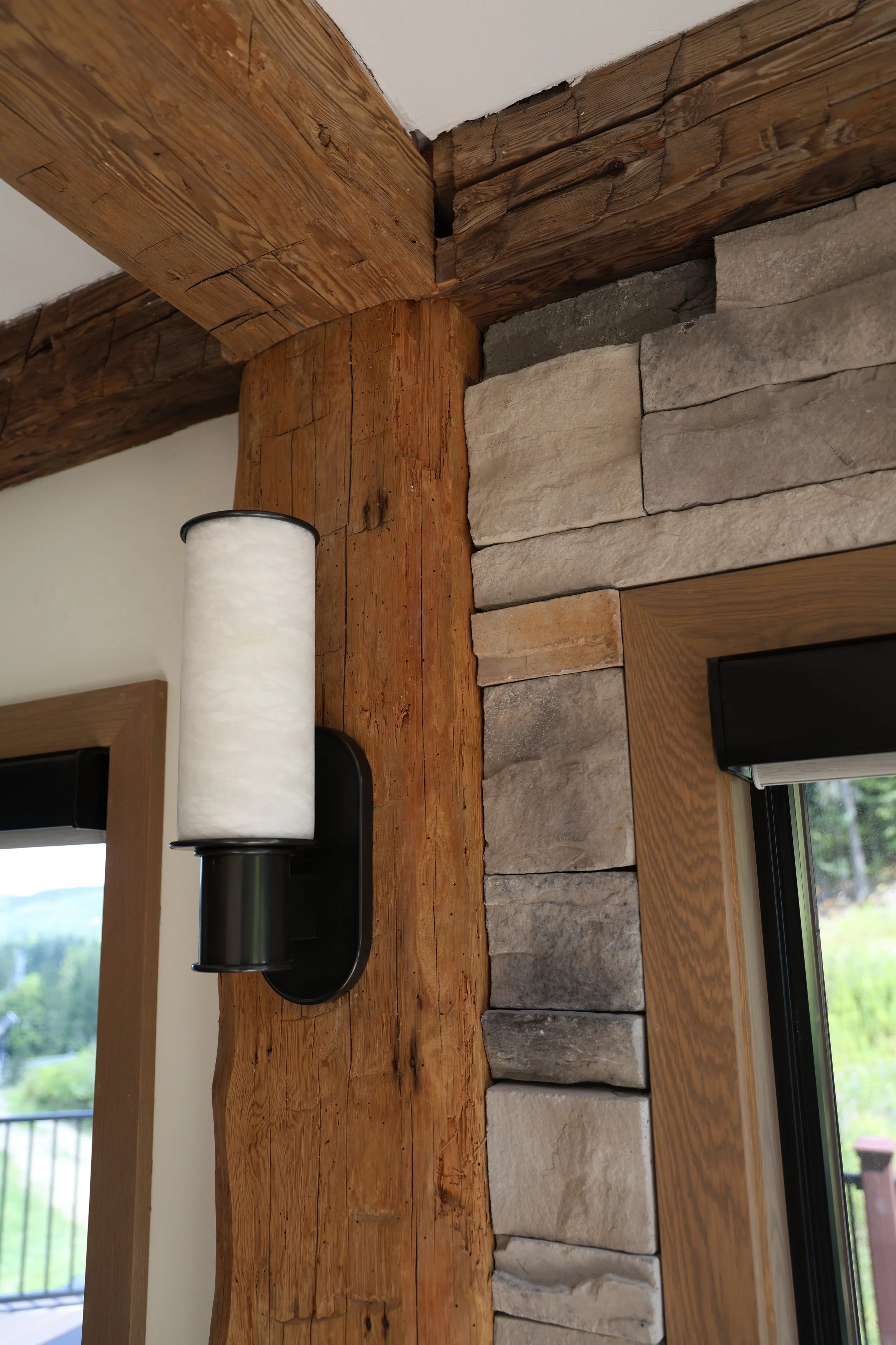 Renovation in Ellicottville, NY showing a reclaimed wooden beam, a stone wall, and a window with natural light.